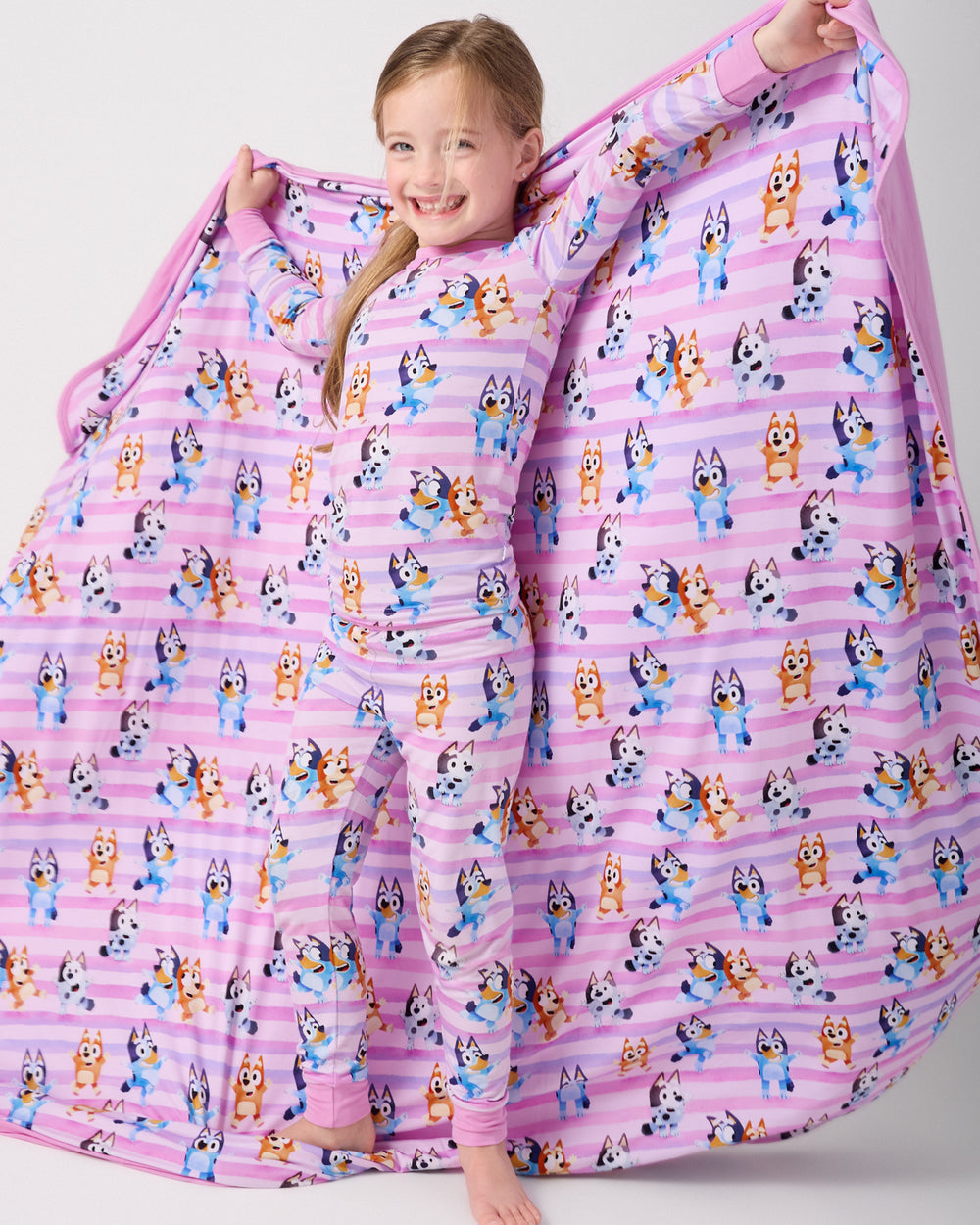 Standing girl holding out the Pink Bluey Dance All Day Large Cloud Blanket®