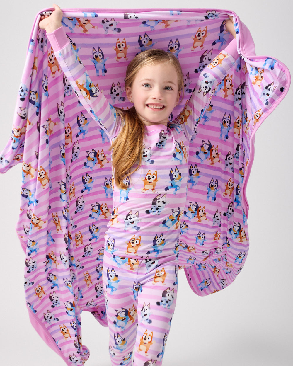 Girl wearing the Pink Bluey Dance All Day Two-Piece Pajama Set holding the matching blanket