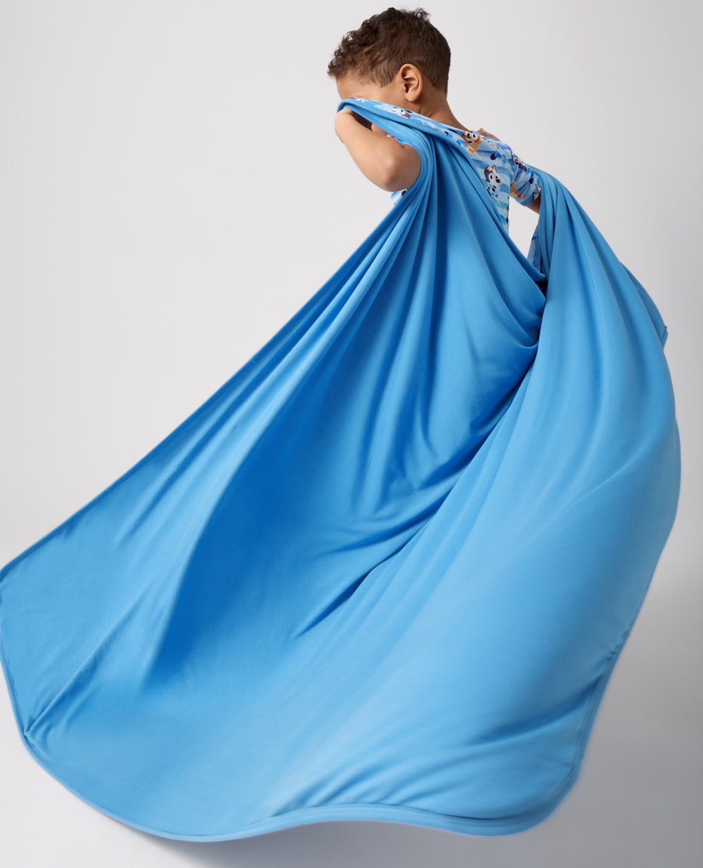 Boy holding the Bluey Dance All Day Large Cloud Blanket® showing the solid blue side
