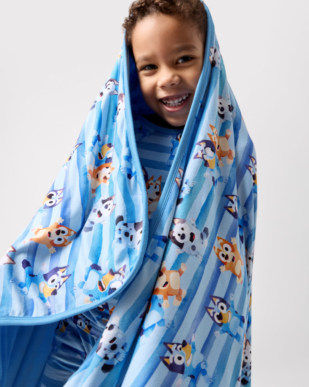 Close up of boy wrapped in the Bluey Dance All Day Large Cloud Blanket®