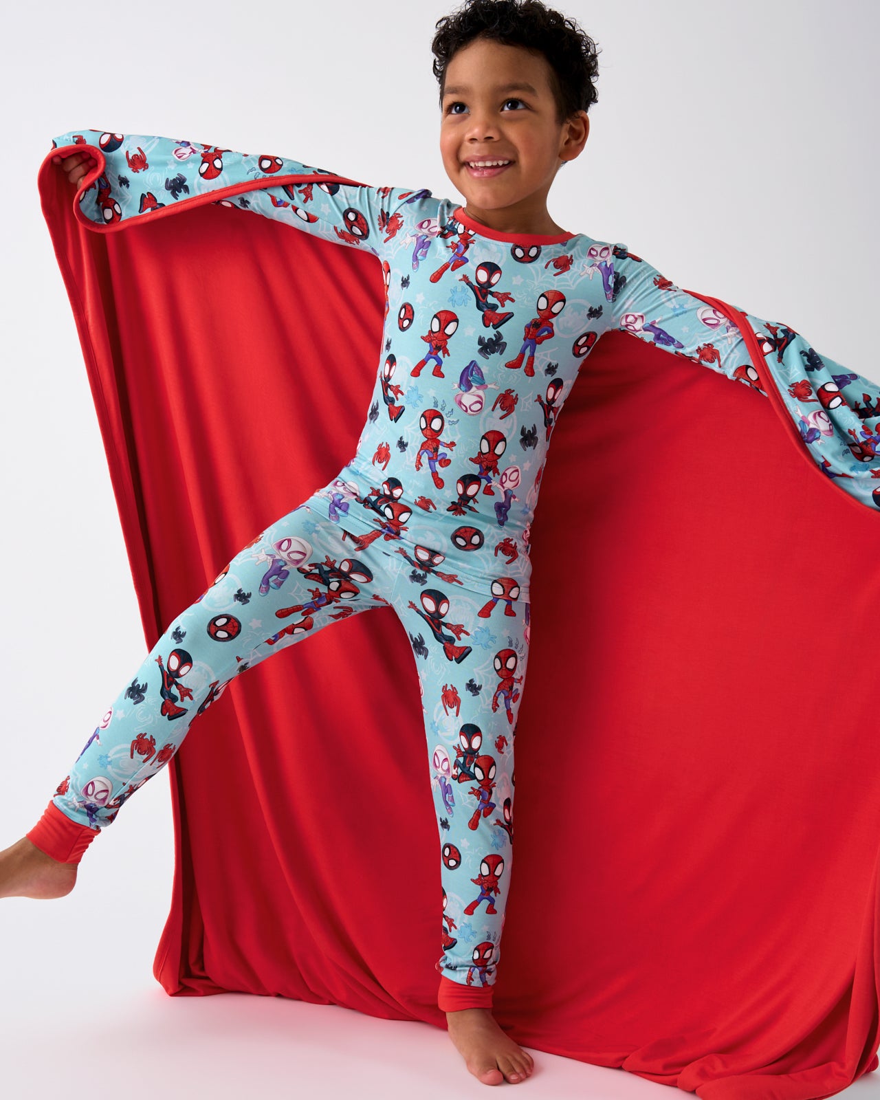 Boy holding out the Spidey & Friends Tiny Webs Large Cloud Blanket® showing the solid red side