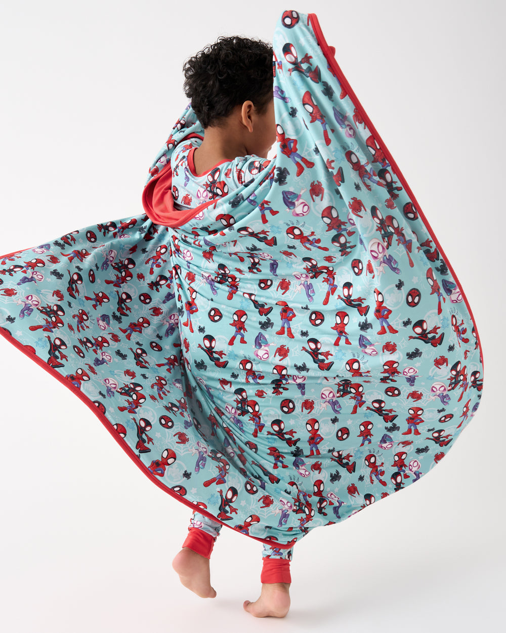 Boy in motion holding the Spidey & Friends Tiny Webs Large Cloud Blanket®