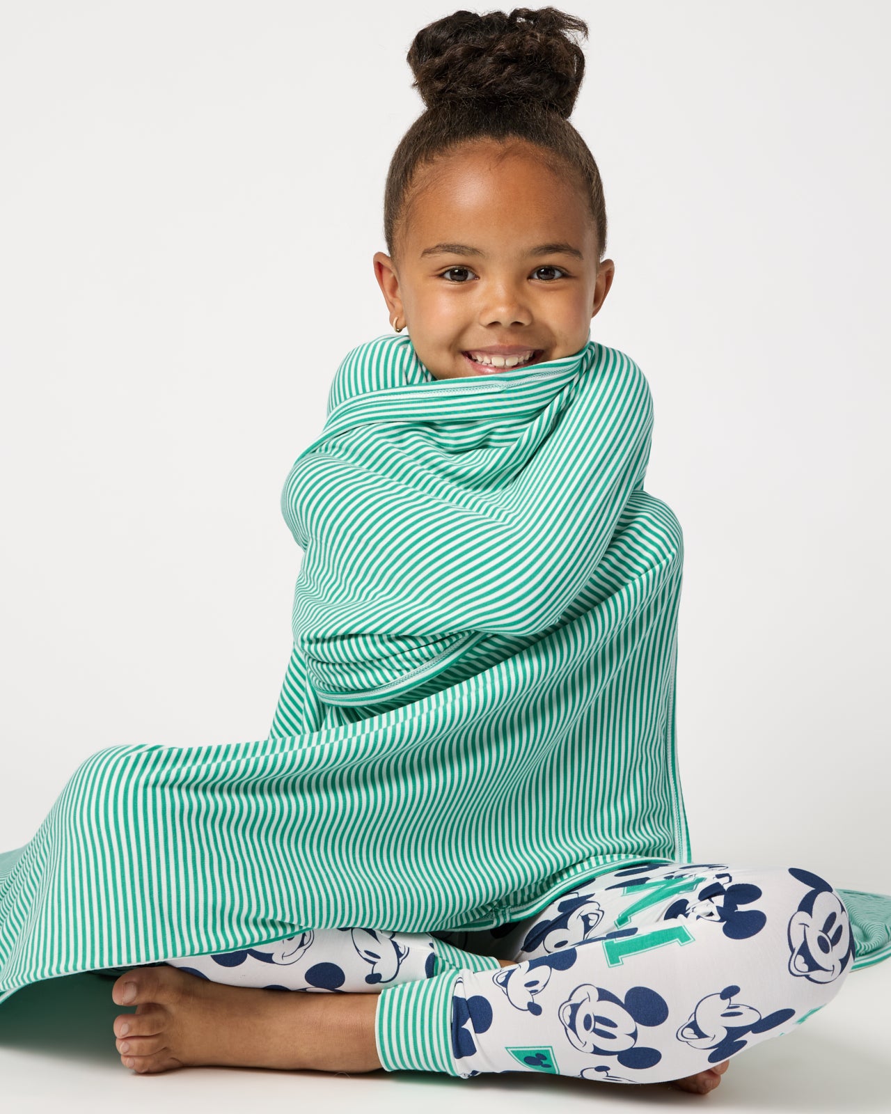 Sitting girl wrapped in the Disney Varsity Mickey Mouse Large Cloud Blanket®