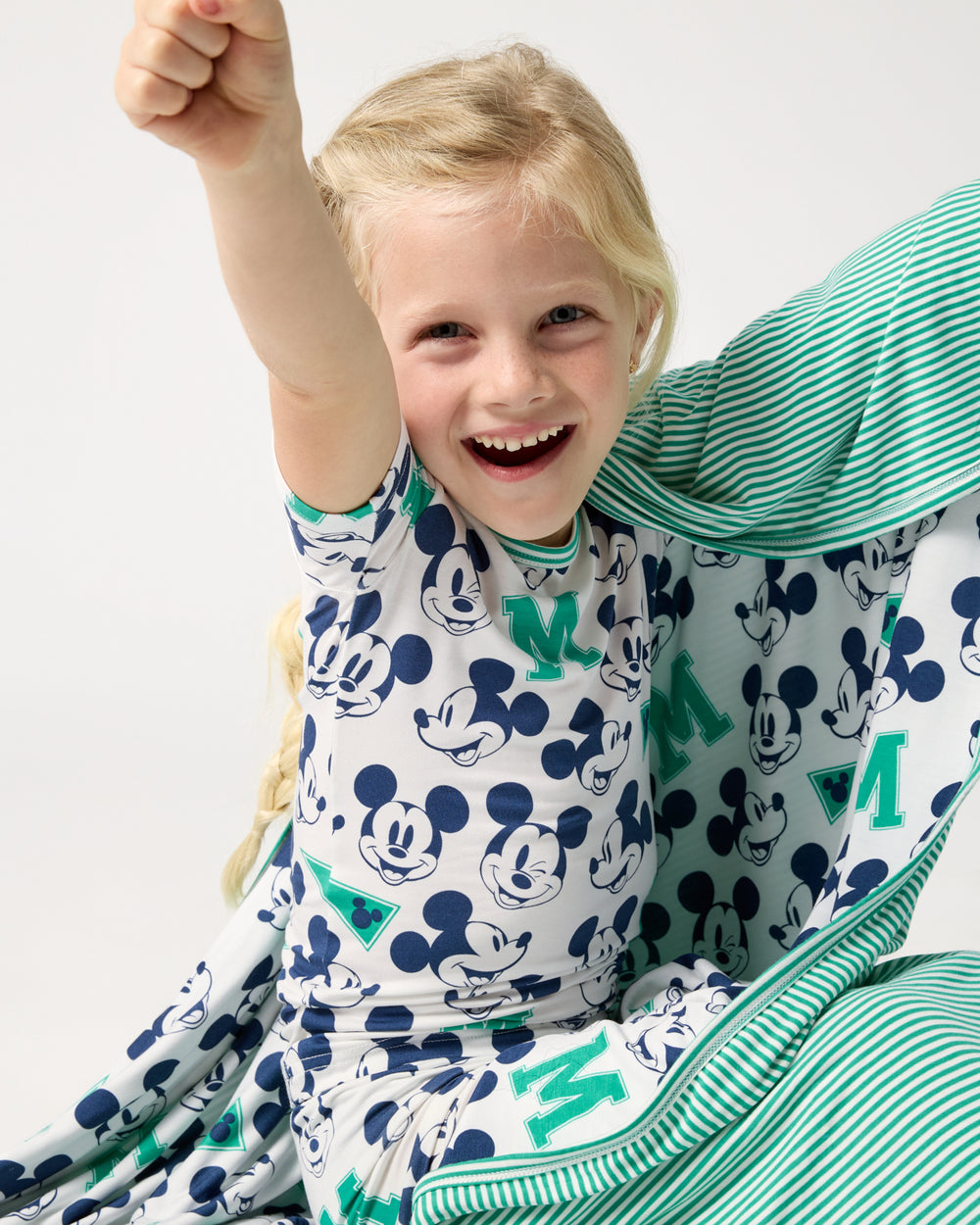 Girl wrapped in the Disney Varsity Mickey Mouse Large Cloud Blanket® wearing matching PJs