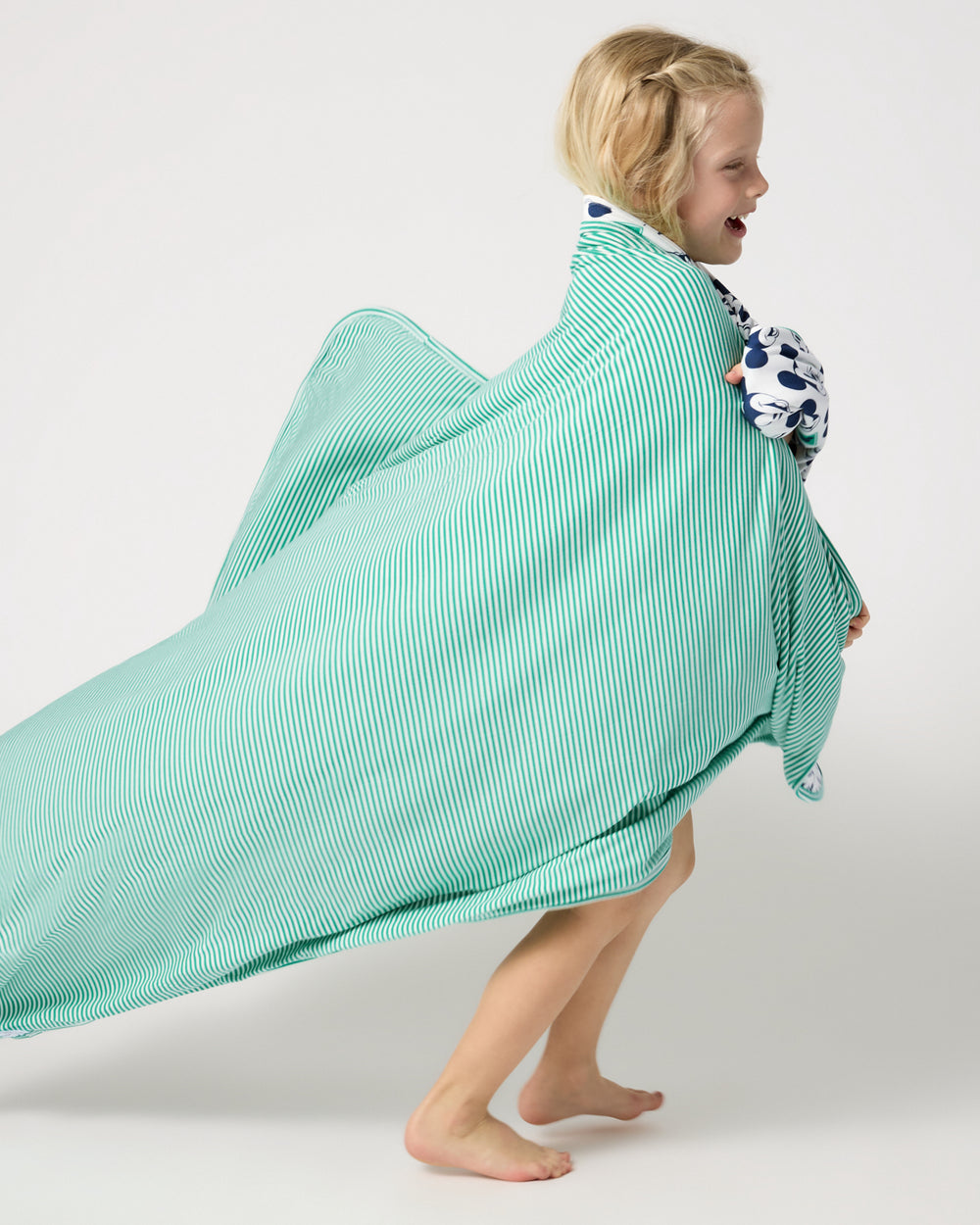 Child wrapped in the Disney Varsity Mickey Mouse Large Cloud Blanket® showing the striped side