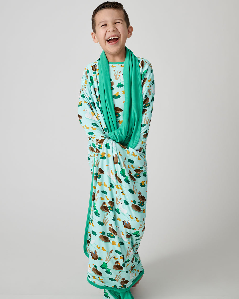 Standing boy wrapped in the Puddle Jumpers Large Cloud Blanket®