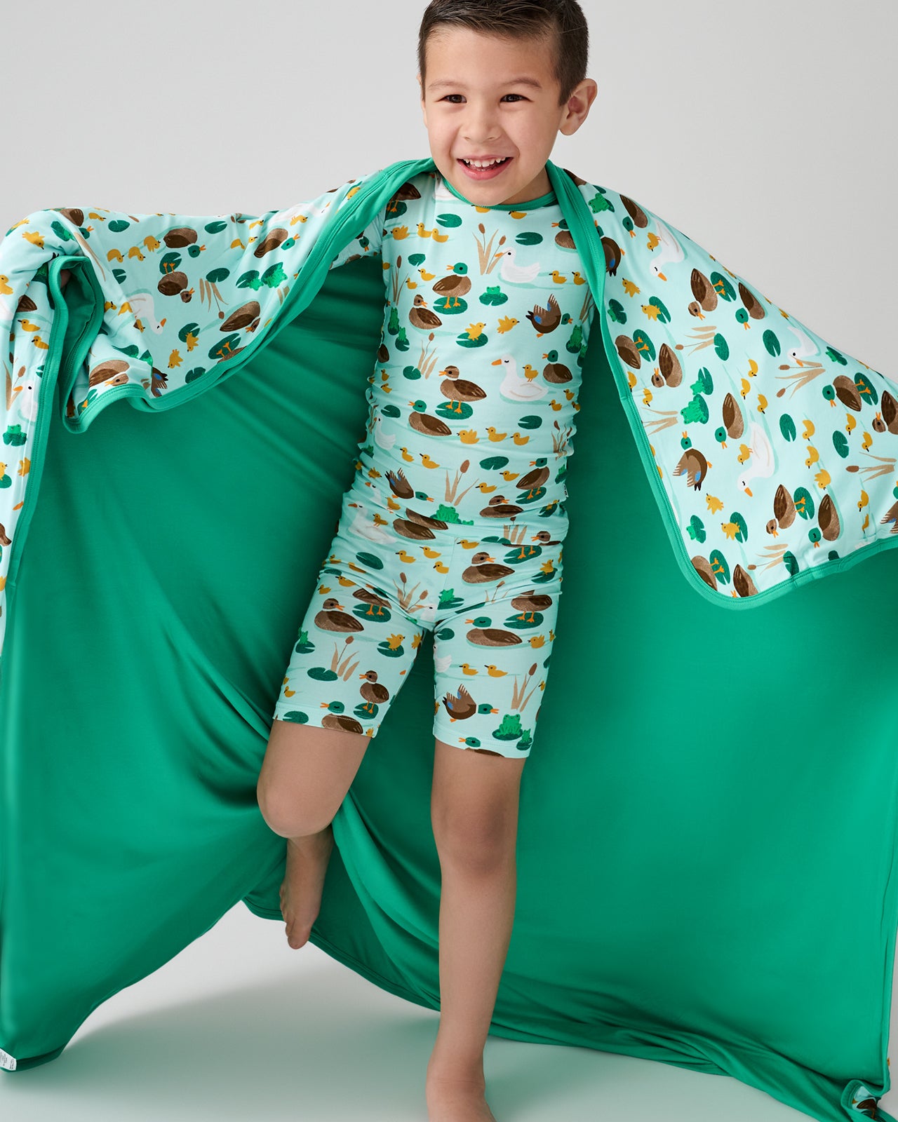 Boy holding up the Puddle Jumpers Large Cloud Blanket® showing the solid green side