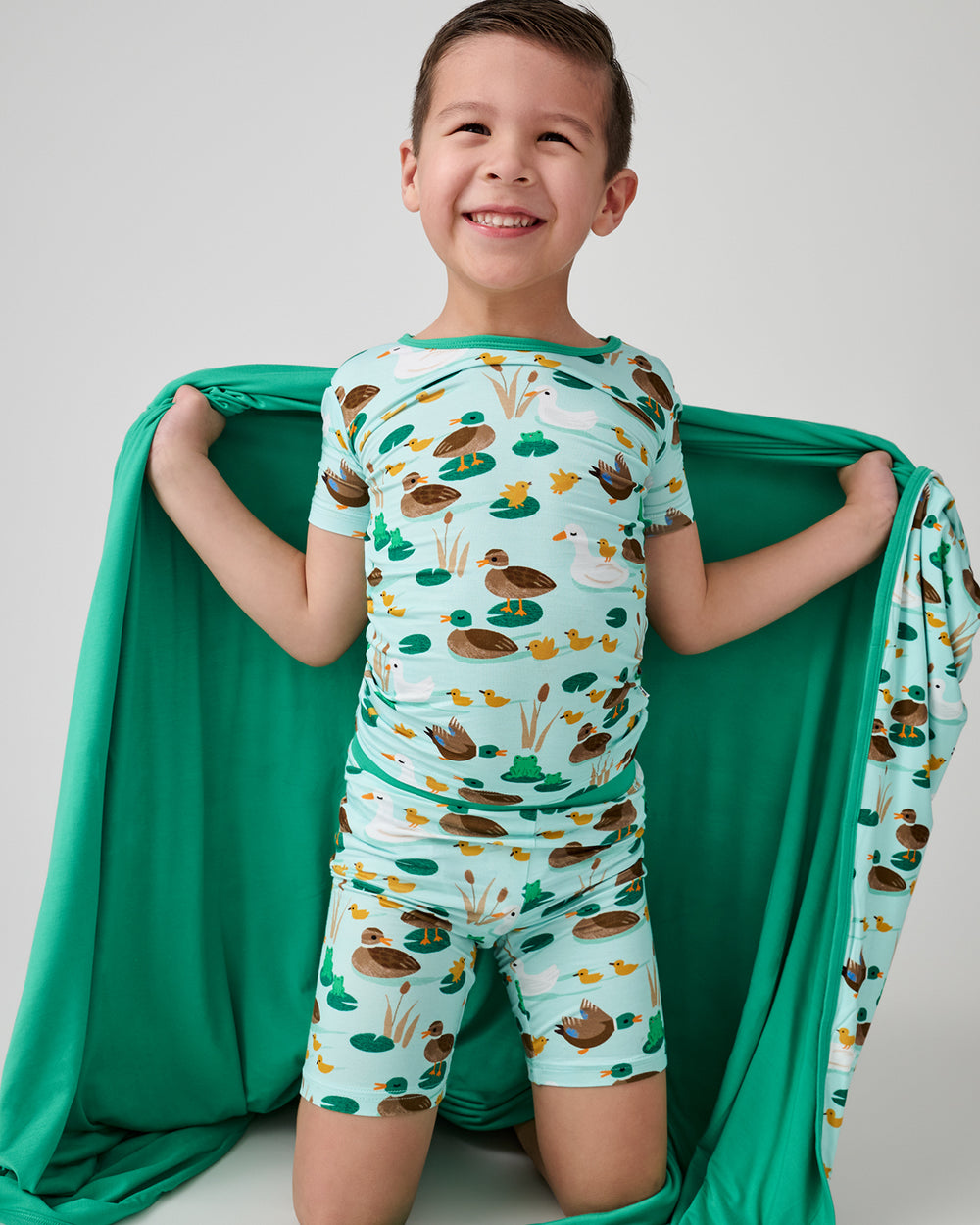 Boy holding the Puddle Jumpers Large Cloud Blanket® wearing matching pajamas