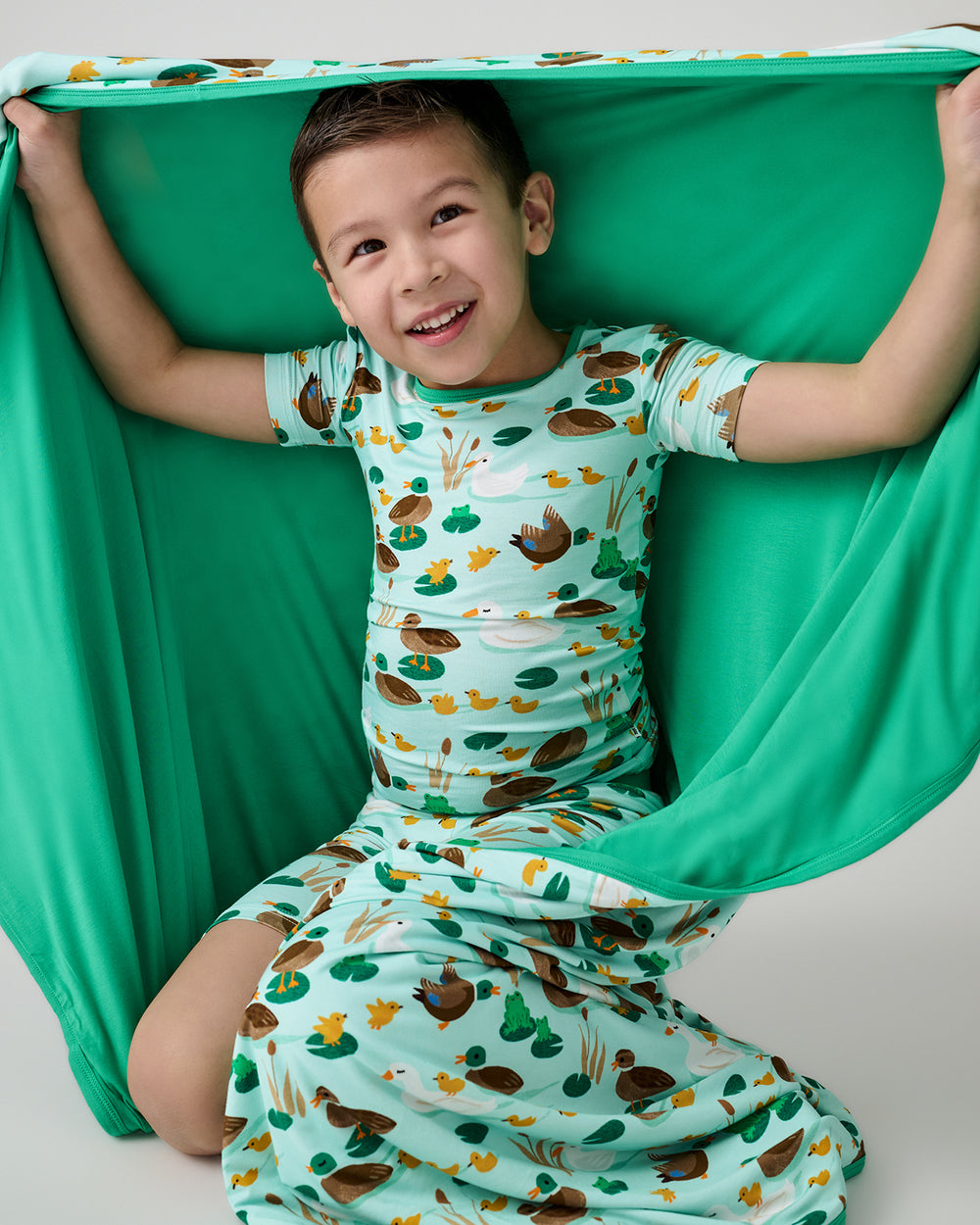 Sitting boy holding up the Puddle Jumpers Large Cloud Blanket®