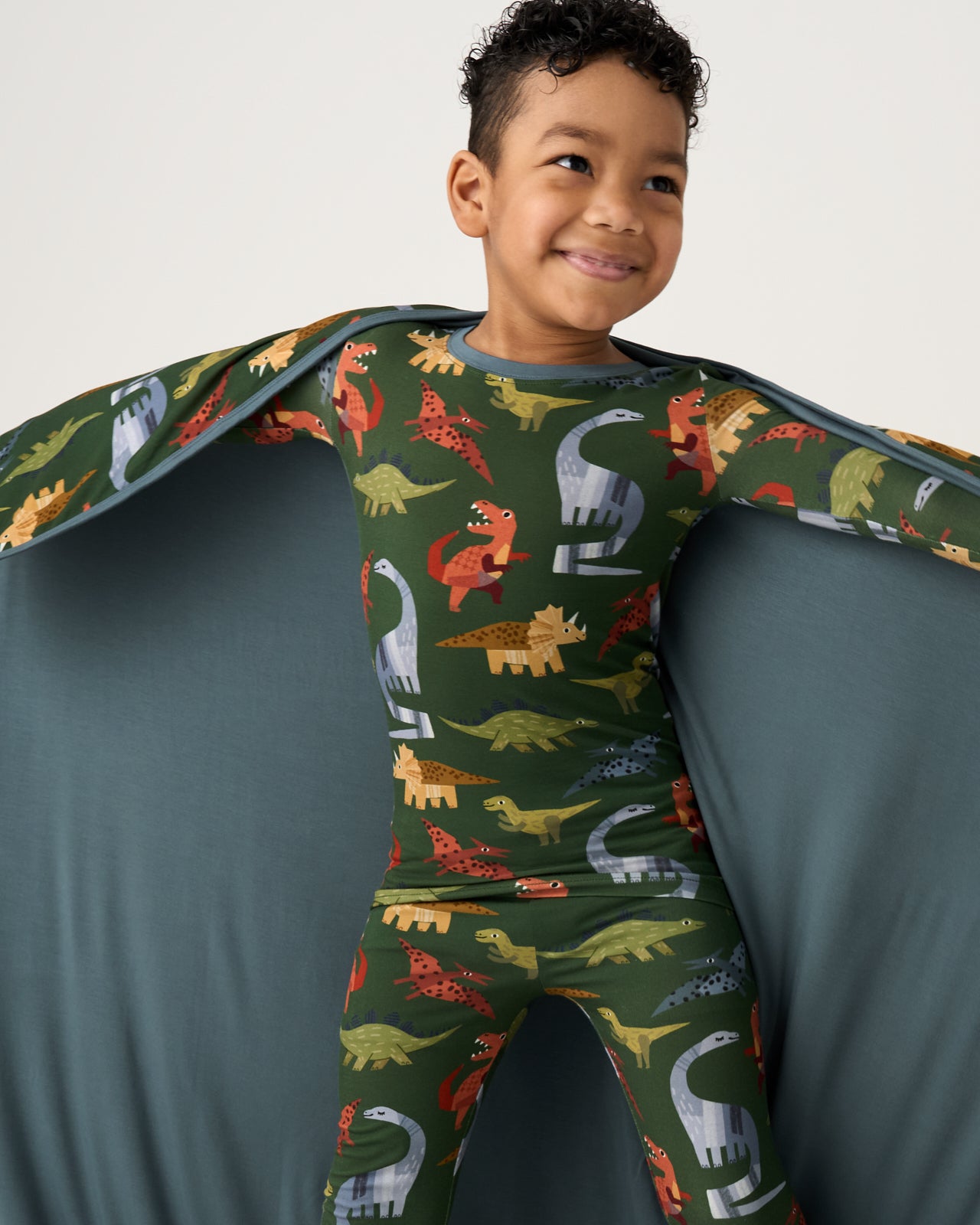 Boy holding out the Green Roar & Explore Large Cloud Blanket® showing the solid green side