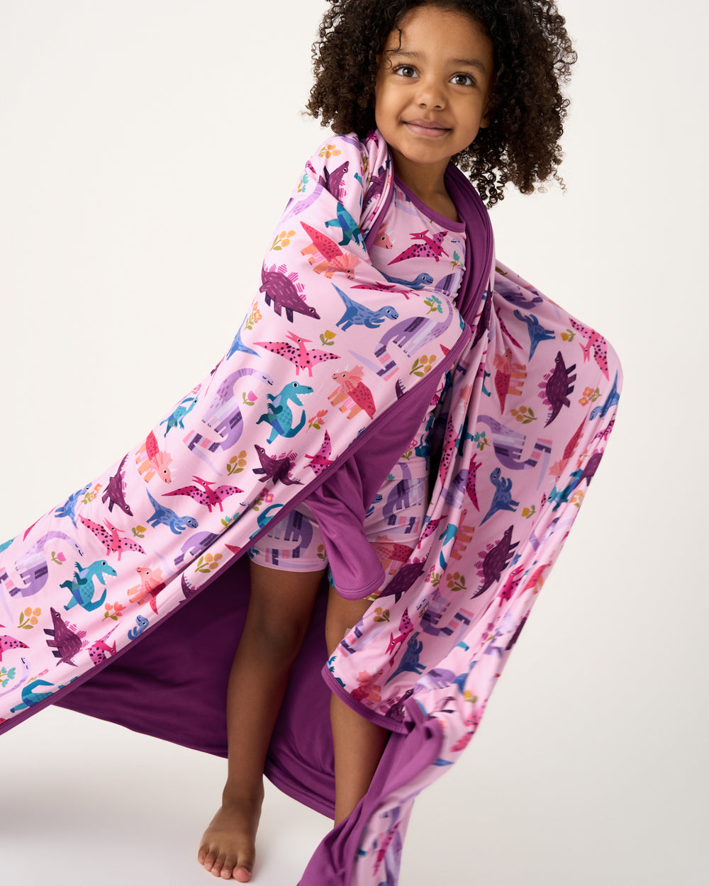 Standing girl wrapped in the Pink Roar & Explore Large Cloud Blanket®