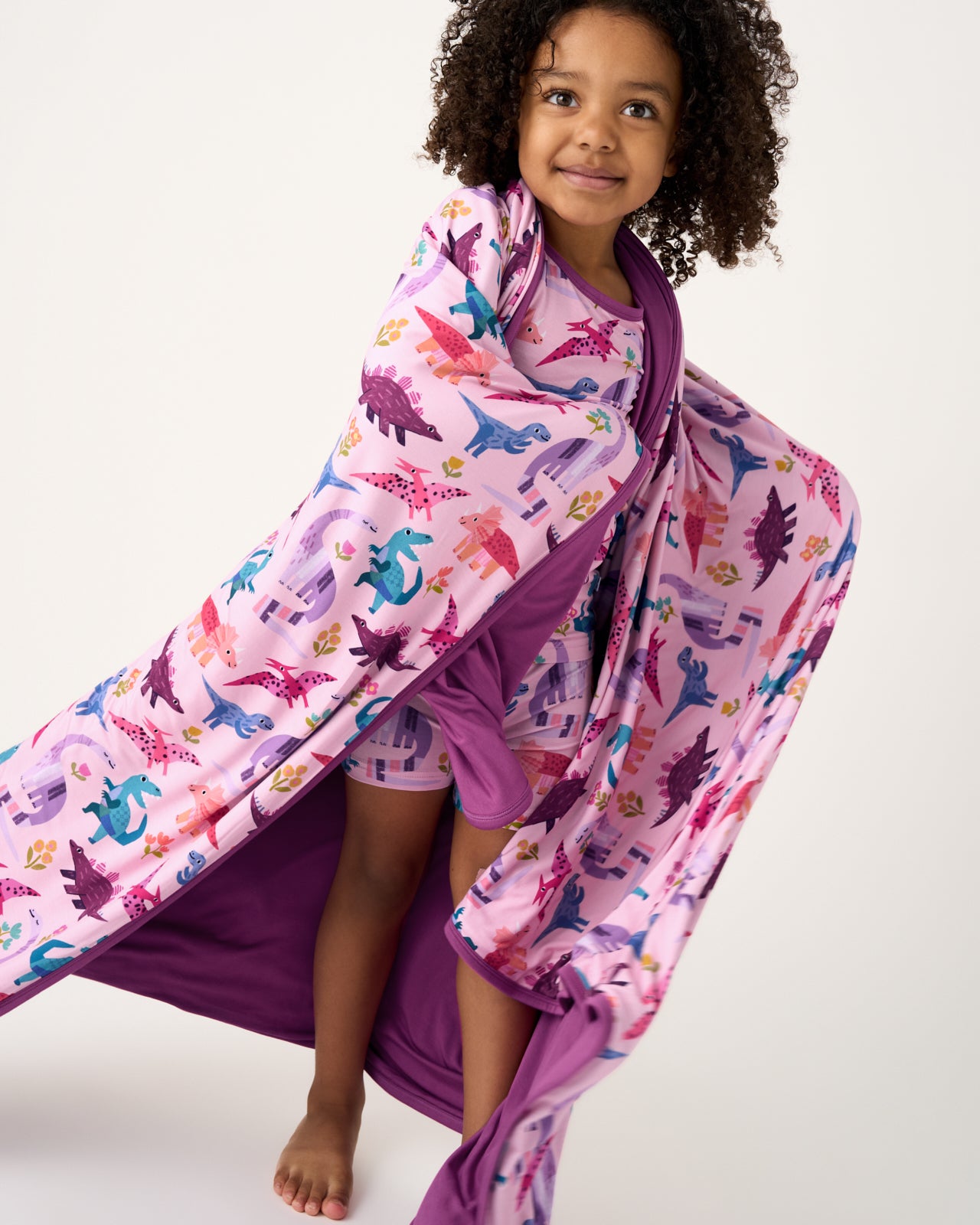 Standing girl wrapped in the Pink Roar & Explore Large Cloud Blanket®