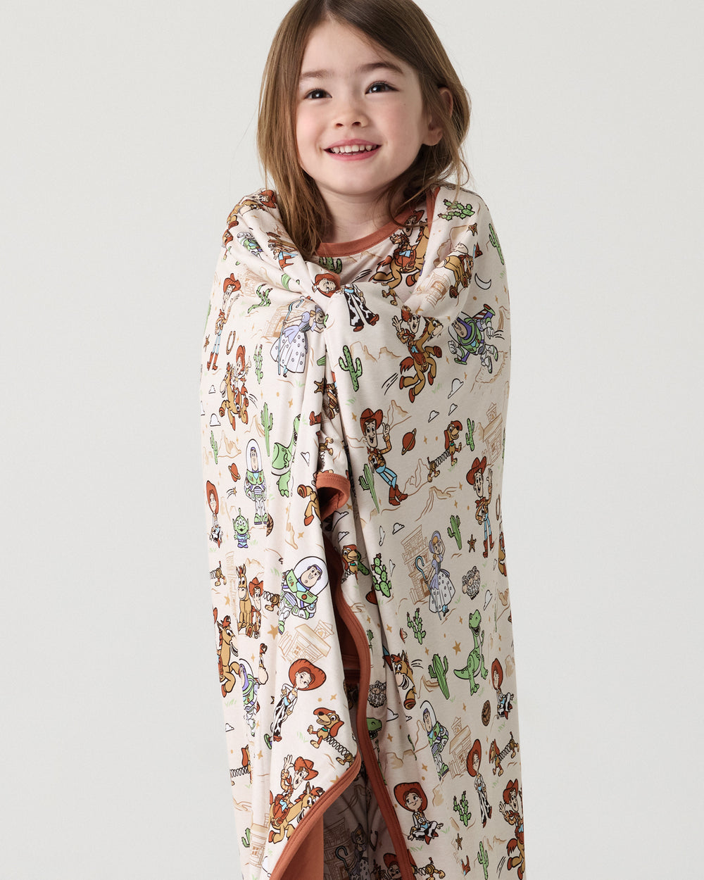 Standing girl wrapped in the Disney & Pixar Woody's Wild West Large Cloud Blanket®