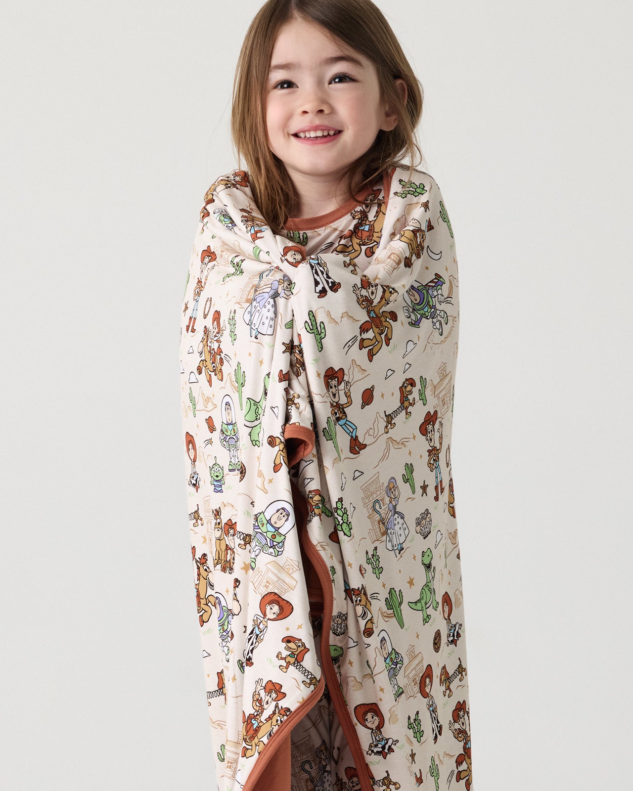 Standing girl wrapped in the Disney & Pixar Woody's Wild West Large Cloud Blanket®