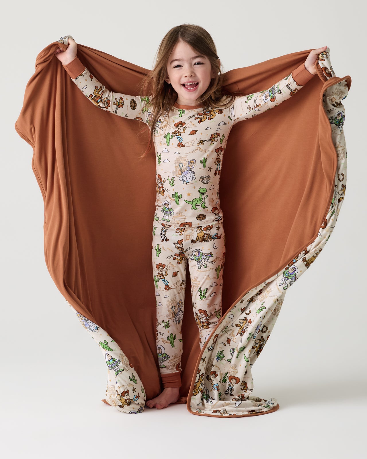 Girl holding out the Disney & Pixar Woody's Wild West Large Cloud Blanket® showing the solid brown side