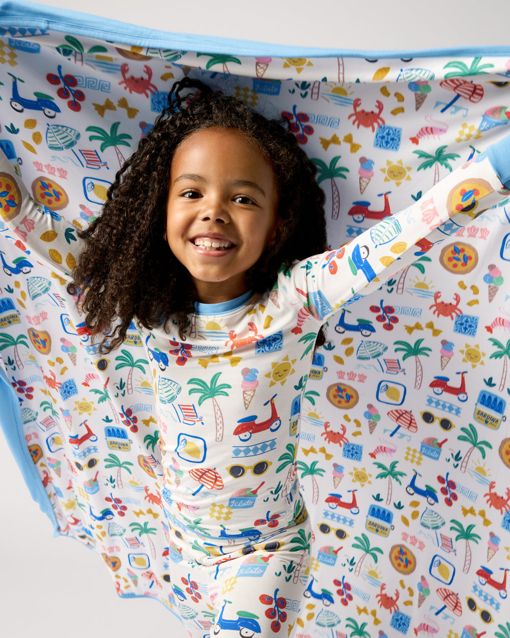 Girl holding the Ciao Bella Large Cloud Blanket® wearing matching pajamas