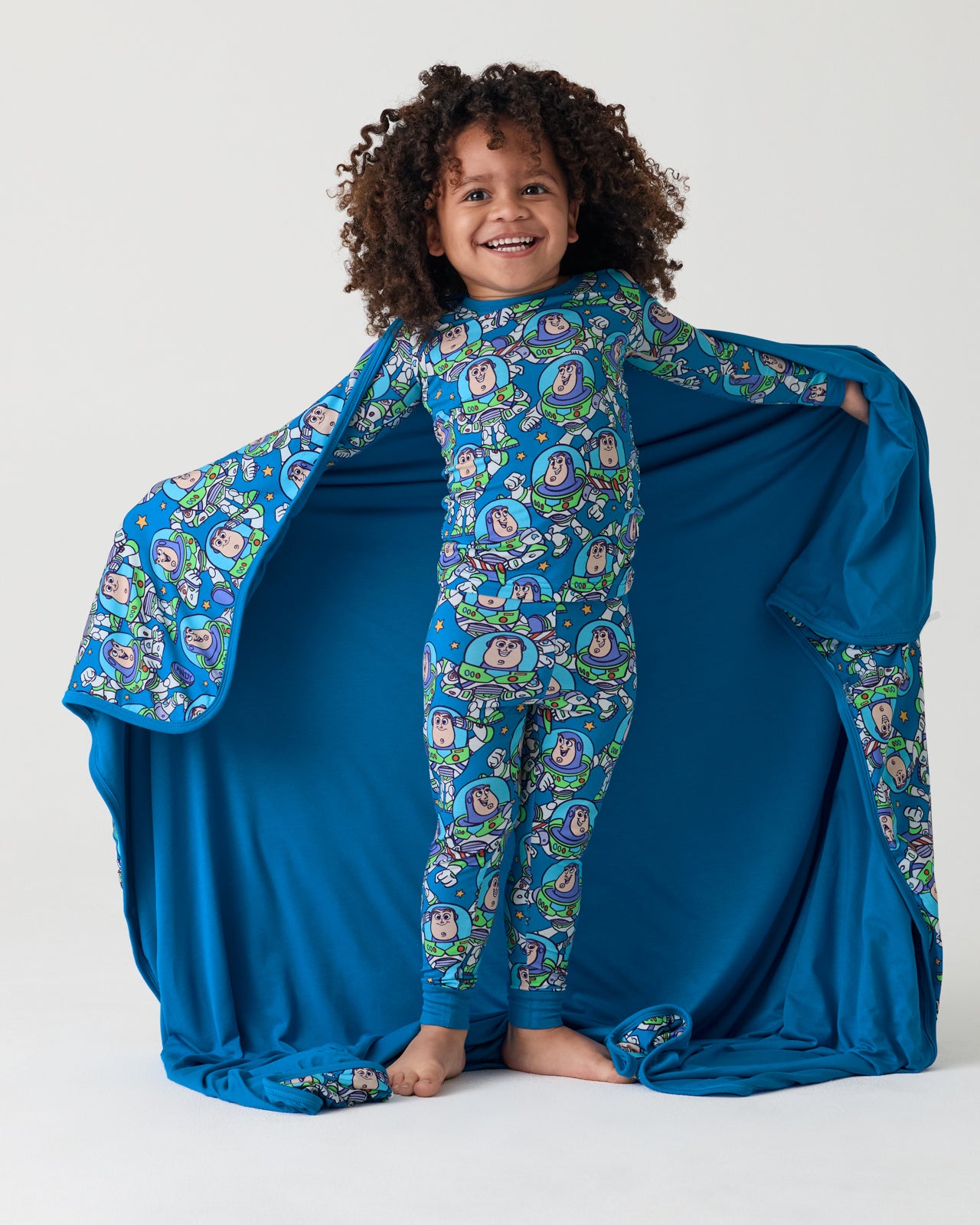 Child holding out the Disney & Pixar Buzz's Cosmic Crew Large Cloud Blanket® showing the solid blue side