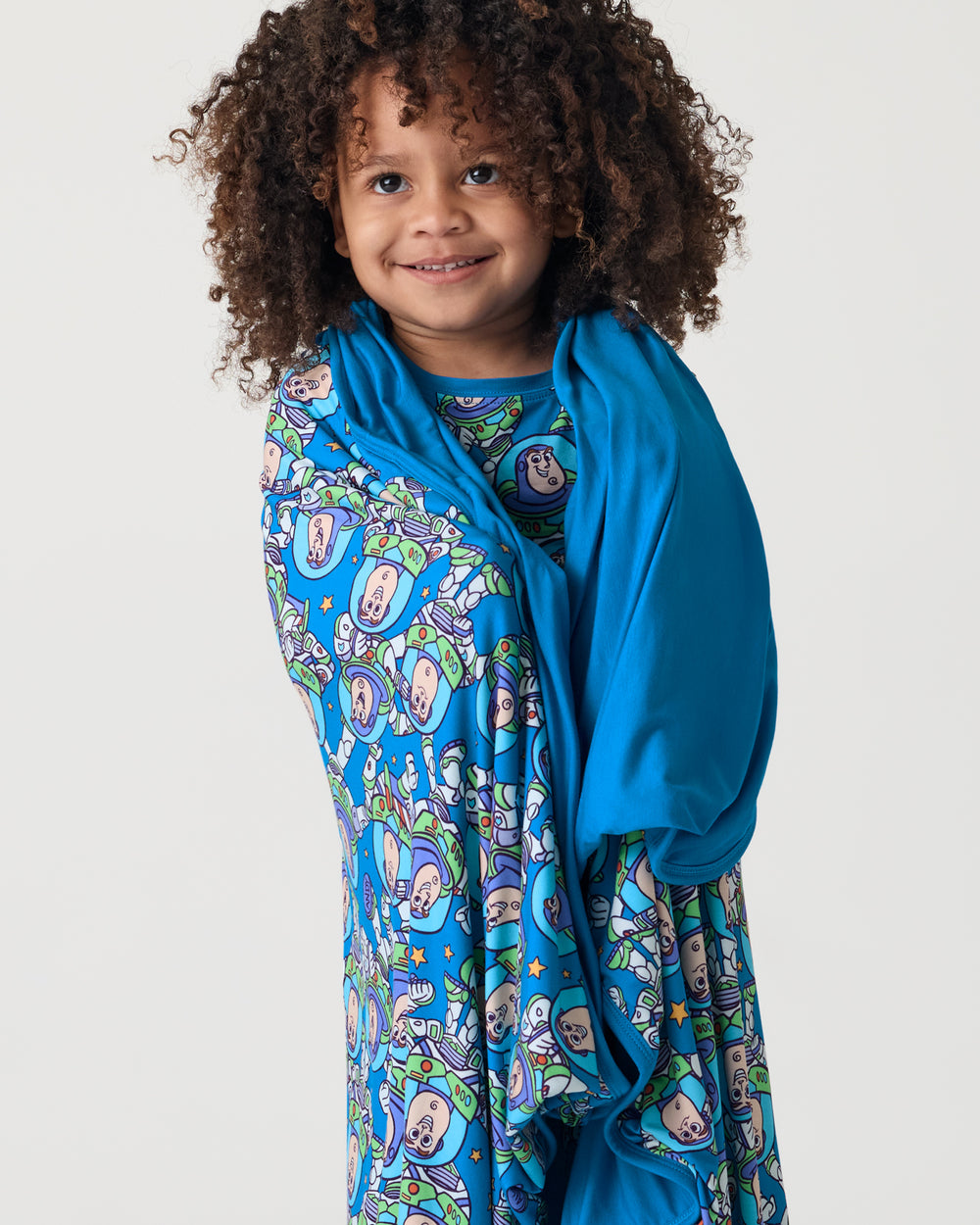 Child wrapped in the Disney & Pixar Buzz's Cosmic Crew Large Cloud Blanket®