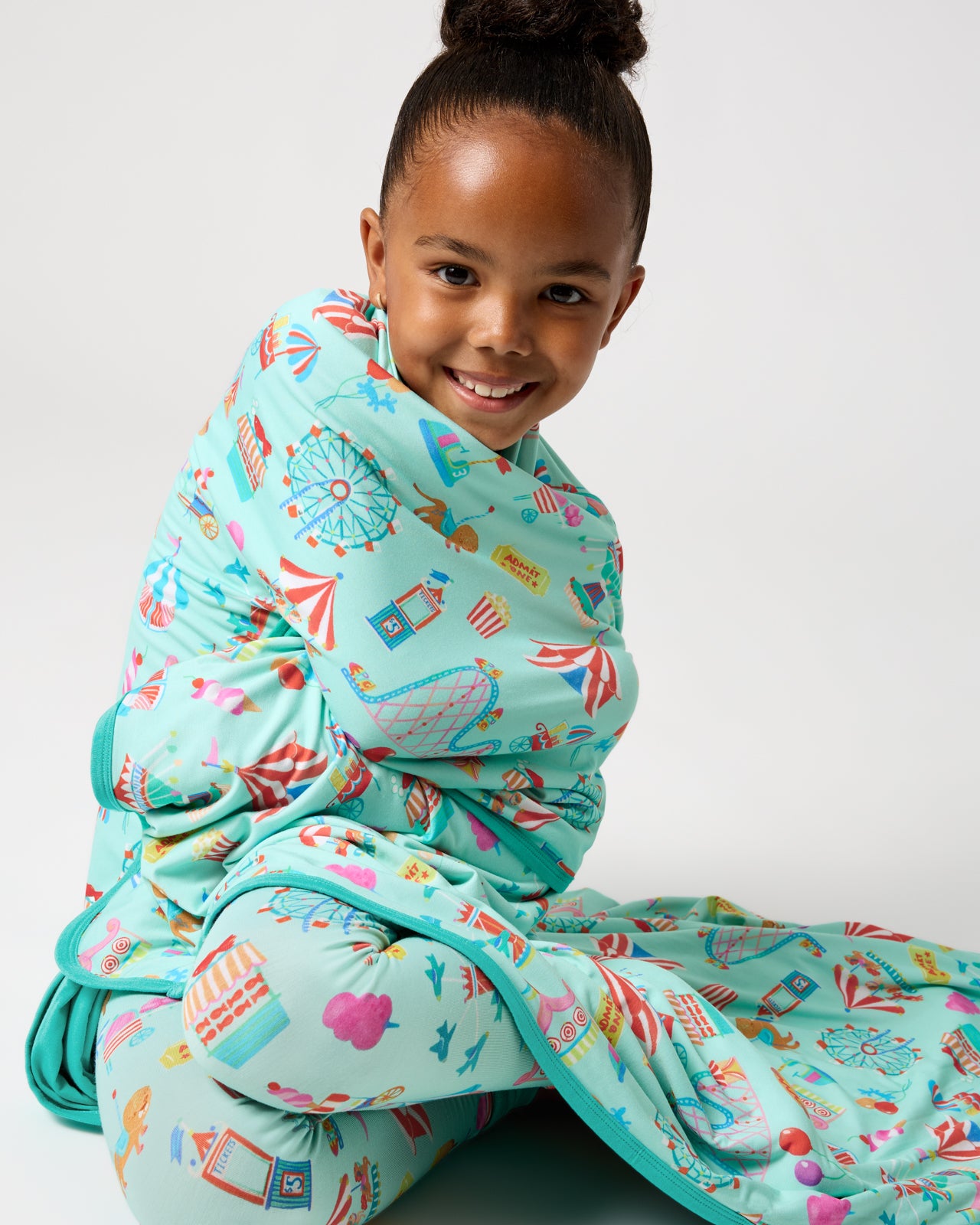 Sitting girl wrapped in the Fizzy Fair Large Cloud Blanket®