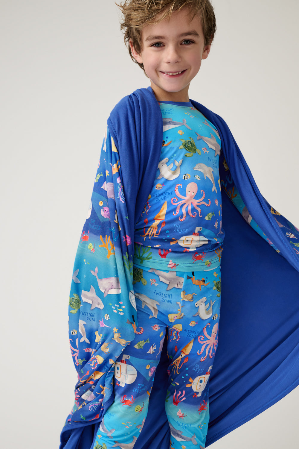 Boy wearing the Underwater Discovery Large Cloud Blanket® draped over his shoulder