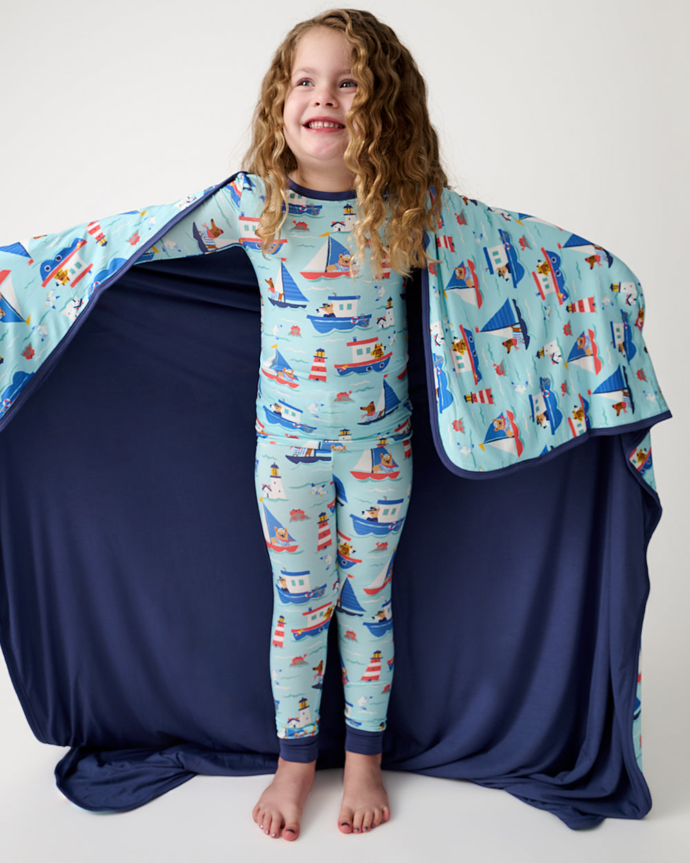 Girl holding out the Nautical Paws Large Cloud Blanket® showing the dark blue side
