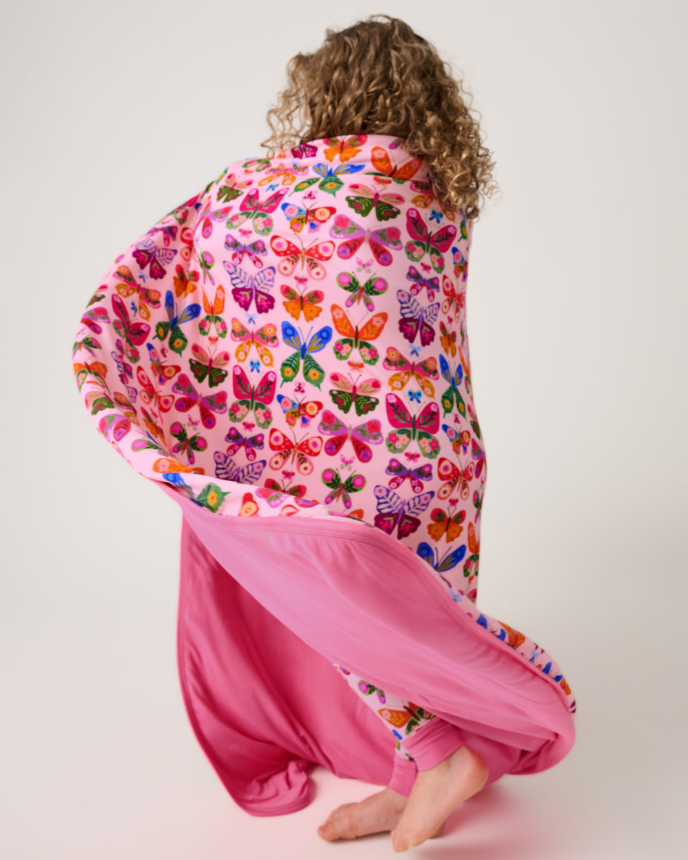 Child in motion wrapped in the Flutter Garden Large Cloud Blanket®