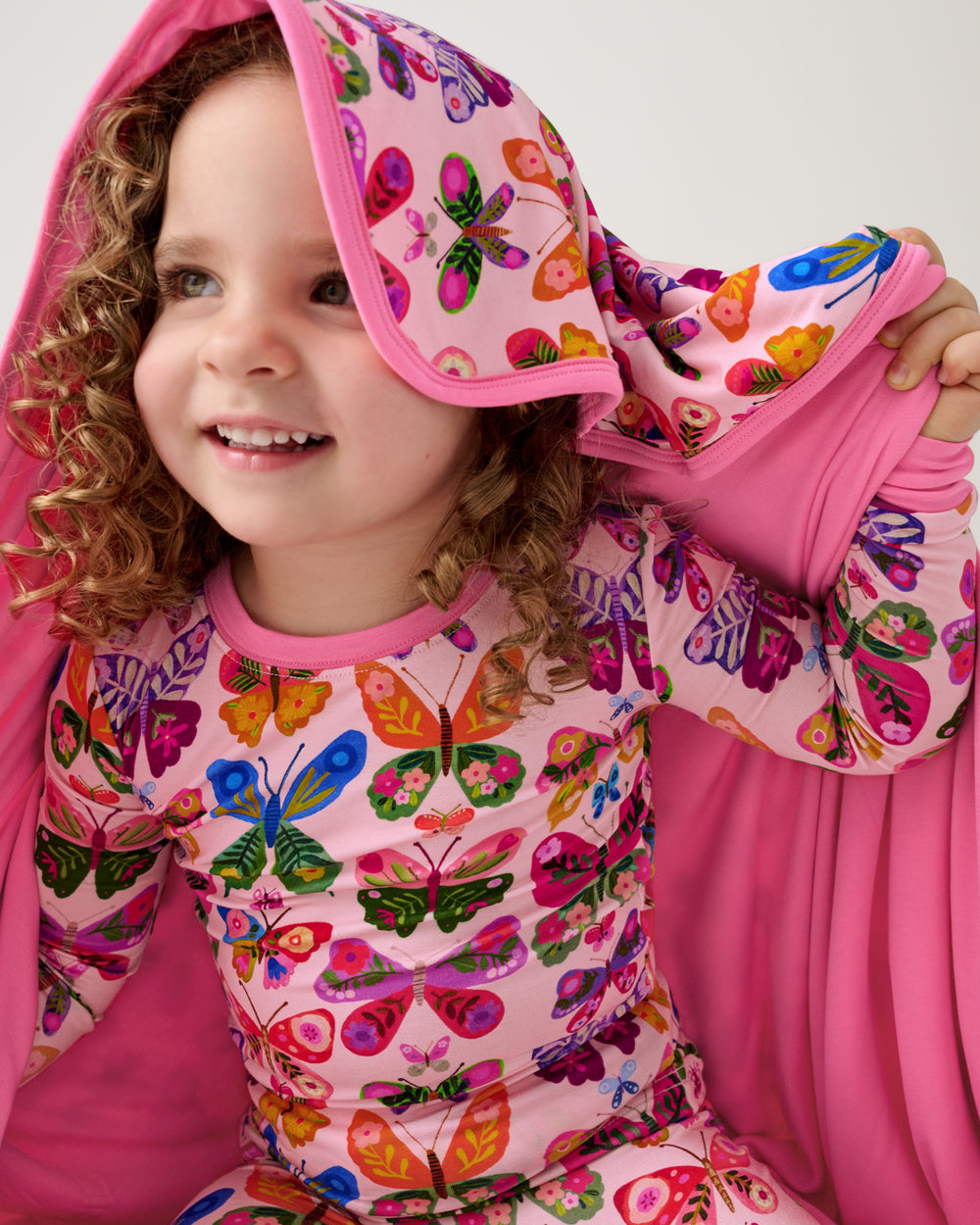 Close up of girl with the Flutter Garden Large Cloud Blanket® draped over her