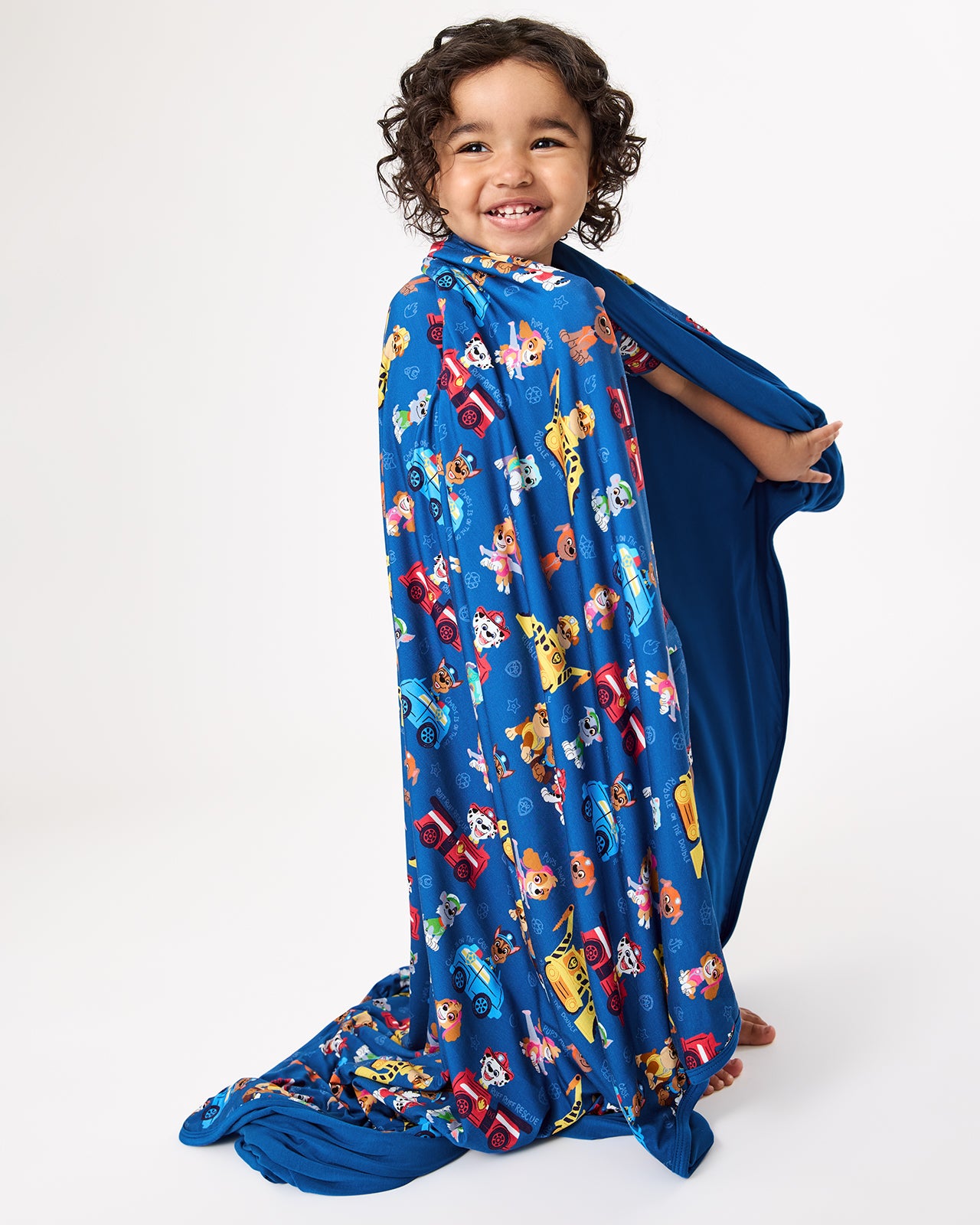 Child wrapped in the PAW Patrol Adventure Bay Heroes Large Cloud Blanket®