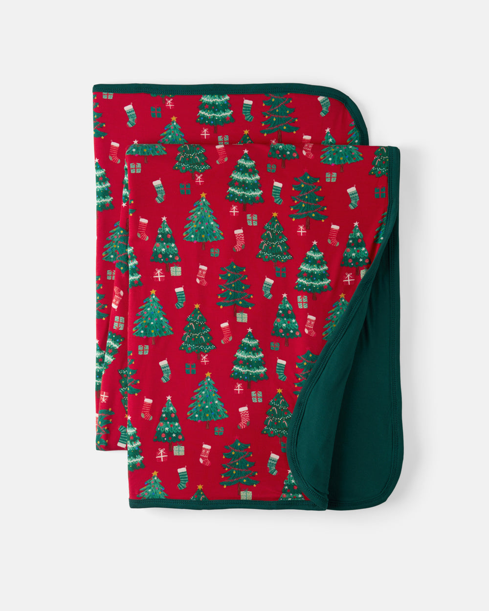 A folded baby blanket with a festive Christmas pattern featuring green trees, stockings, and gifts on a red background, with a solid dark green reverse side, shown on a light gray background.