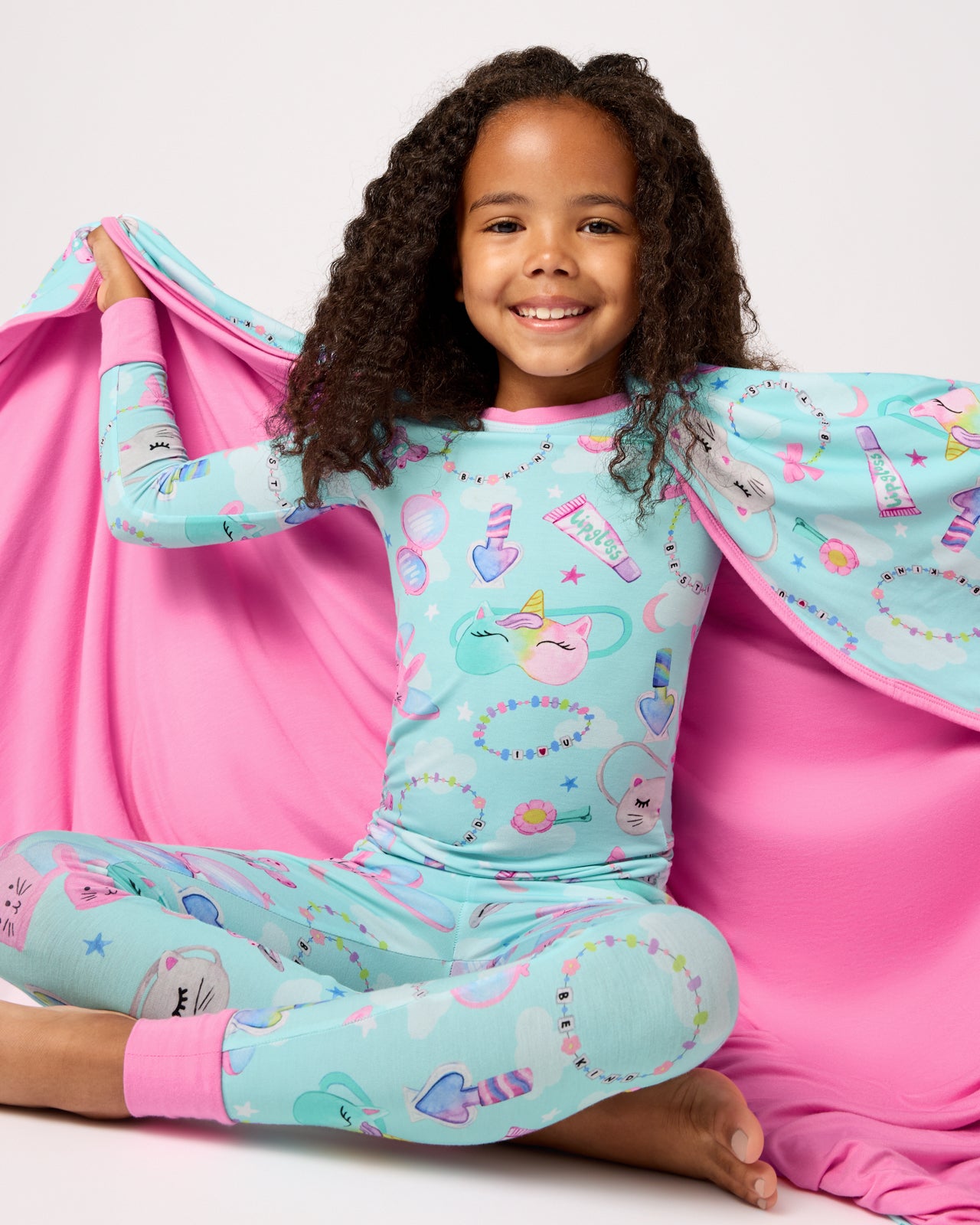 Sitting girl wrapped in the Slumber Club Large Cloud Blanket®