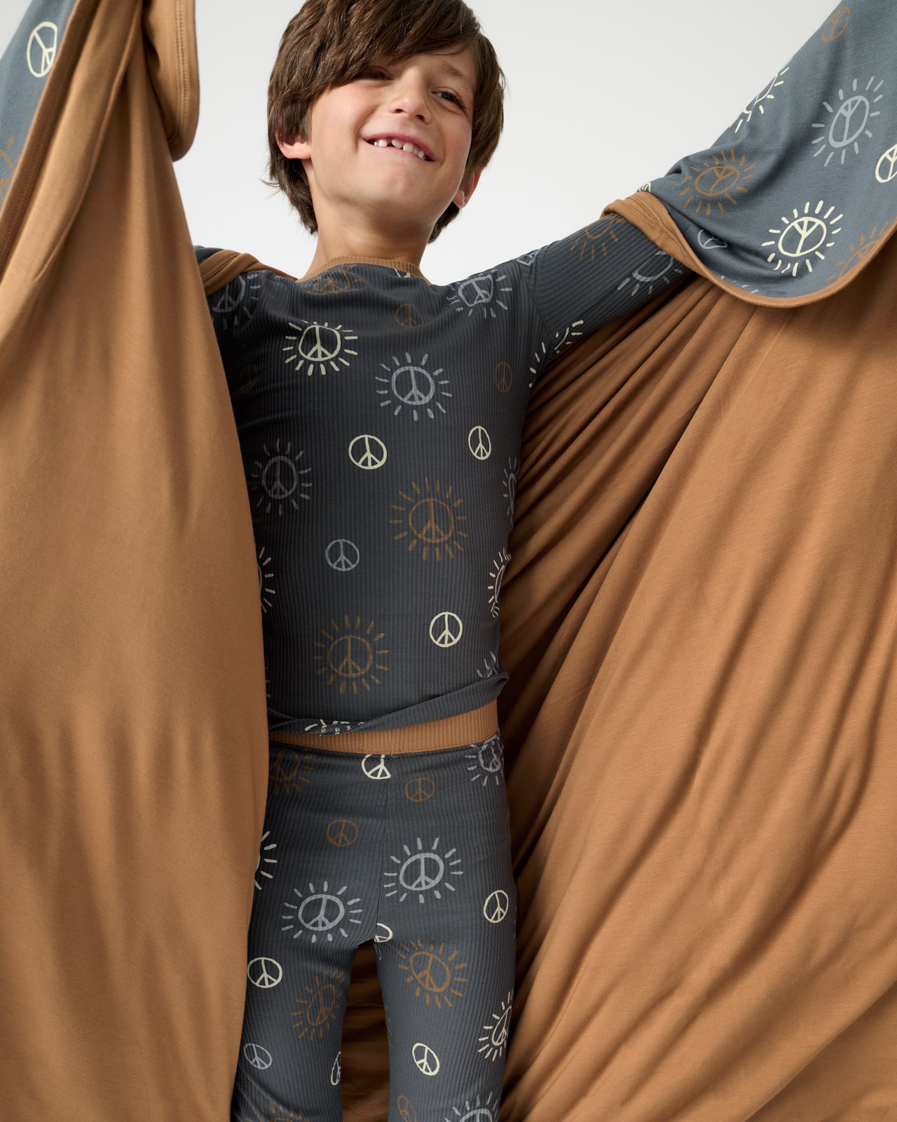 Boy holding up the Peace & Love Large Cloud Blanket® showing the solid brown side