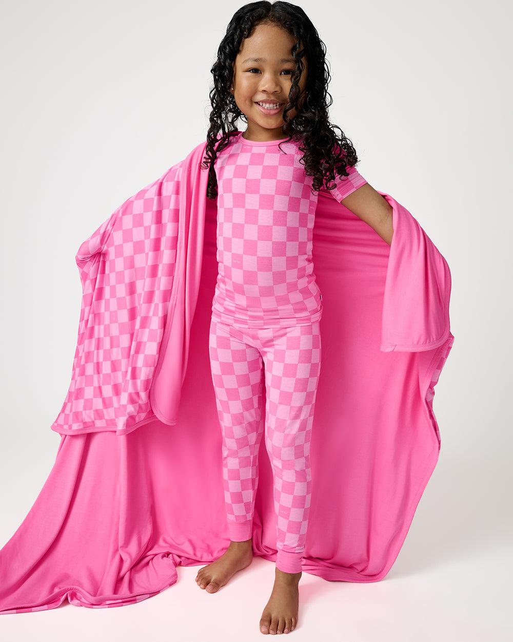 Standing girl wrapped in the Sweet Raspberry Checks Large Cloud Blanket®