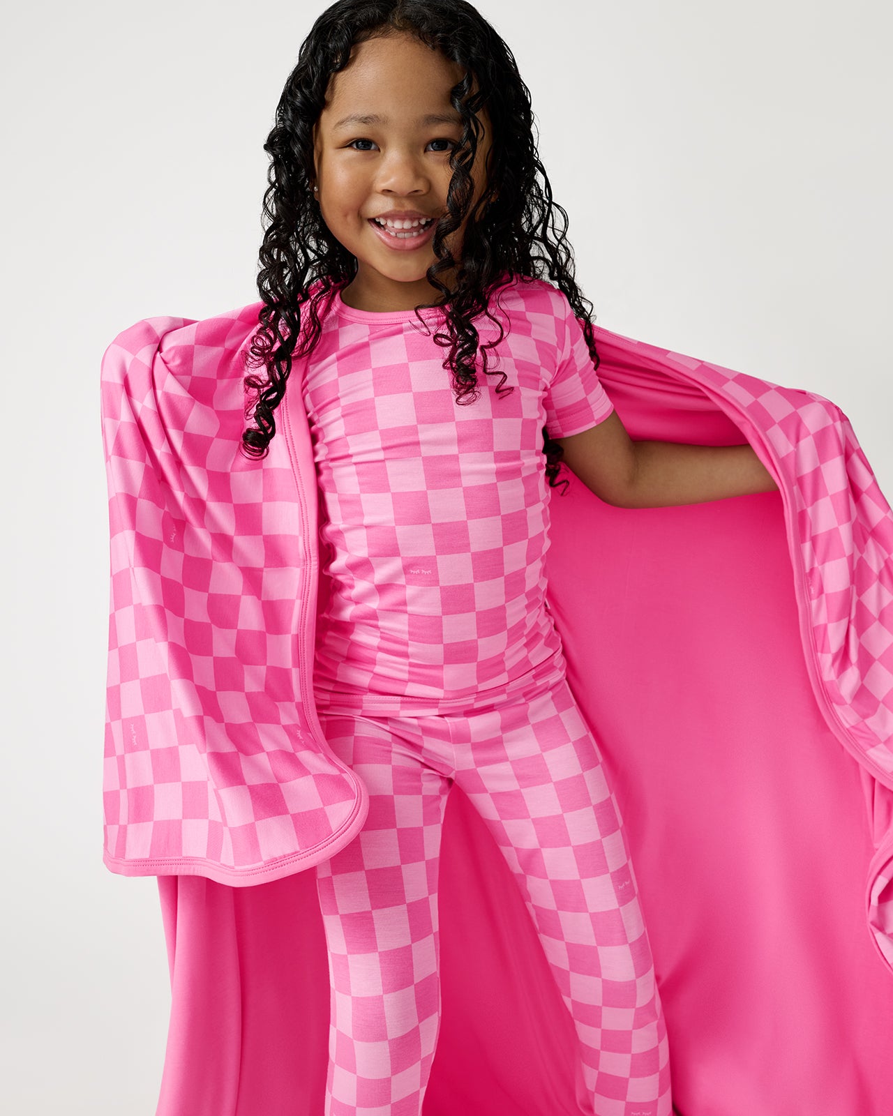 Girl wrapped in the Sweet Raspberry Checks Large Cloud Blanket® wearing matching PJs