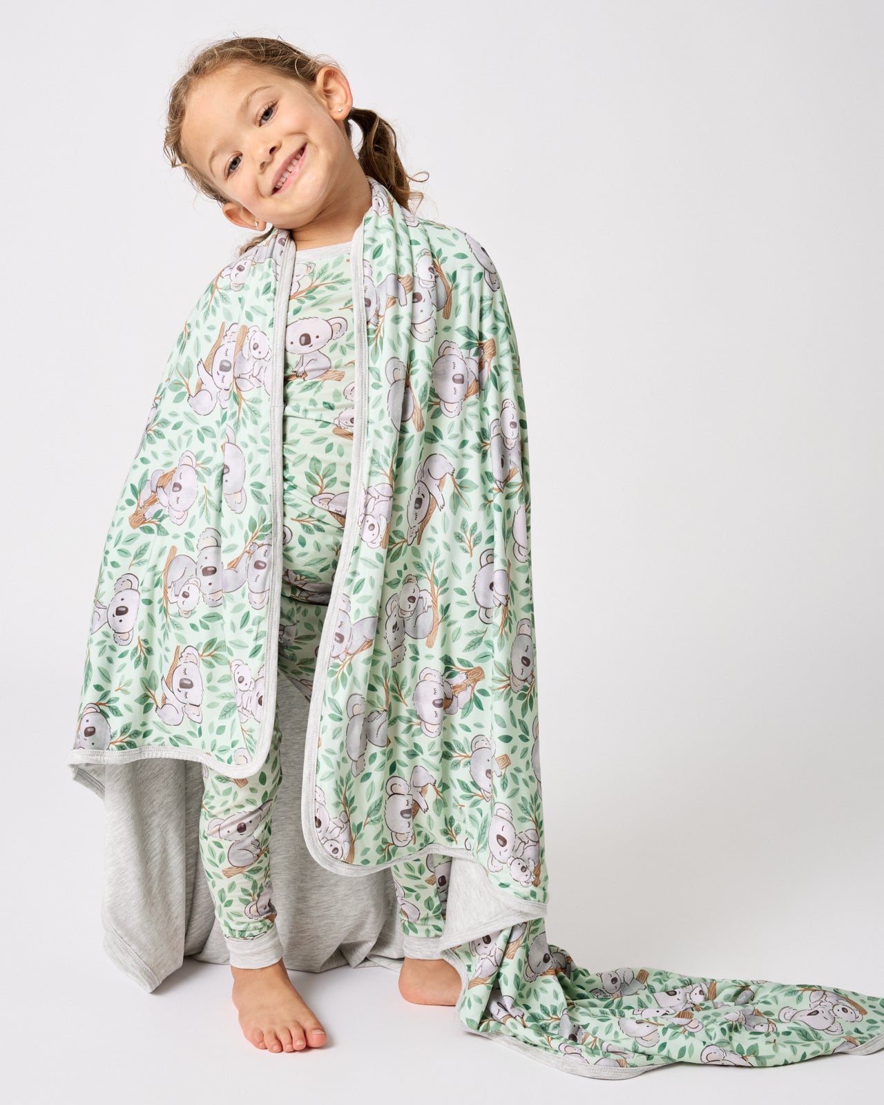 Standing girl wrapped in the Koala Cuddles Large Cloud Blanket®