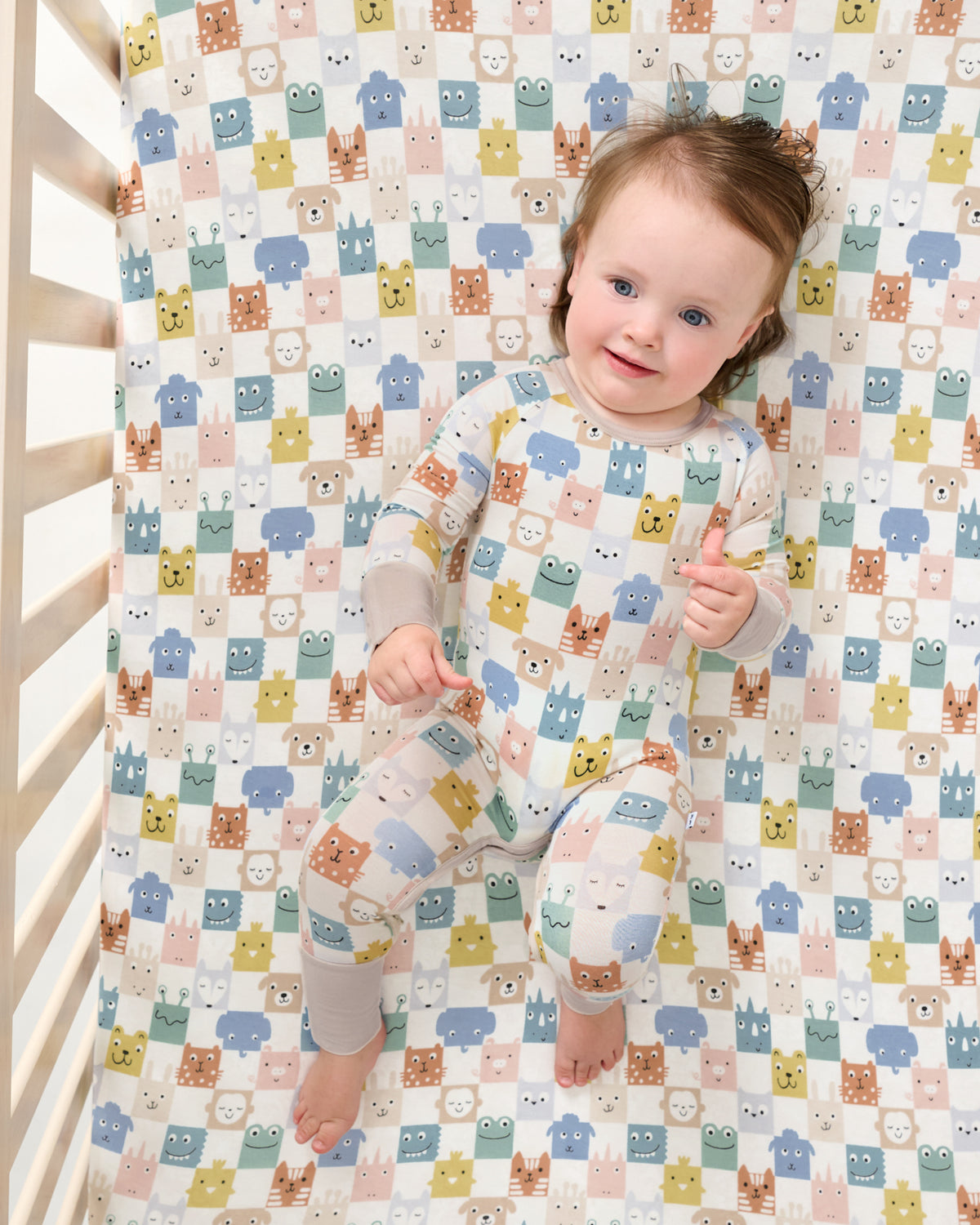 Aerial view of baby on the Check Mates Fitted Crib Sheet wearing a matching zippy