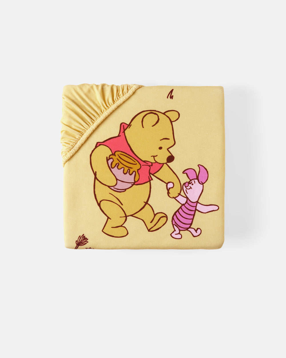 A square baby blanket featuring Winnie the Pooh and Piglet holding hands, in a pale yellow color with a gathered elasticated corner, shown on a light gray background.