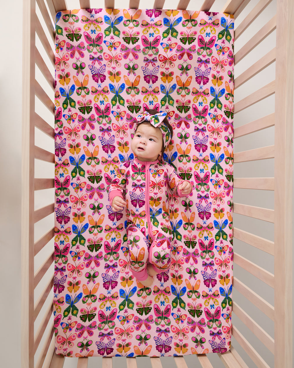 Overhead view of baby laying on the Flutter Garden Fitted Crib Sheet