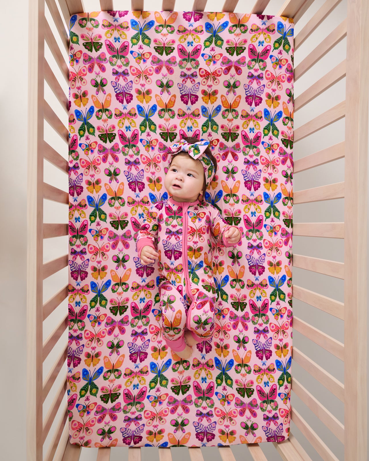 Overhead view of baby laying on the Flutter Garden Fitted Crib Sheet