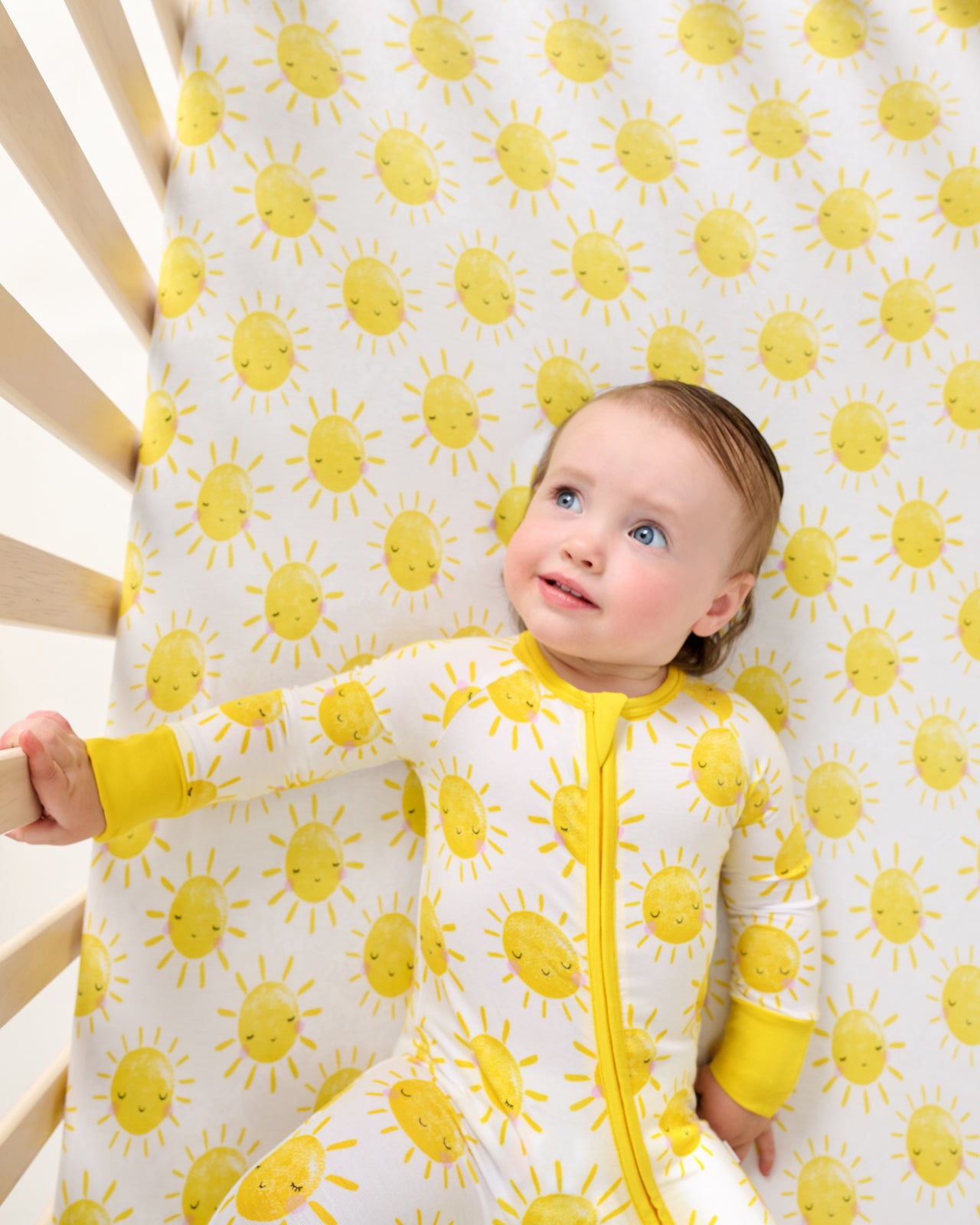 Aerial view of baby laying on the Sunshine Fitted Crib Sheet