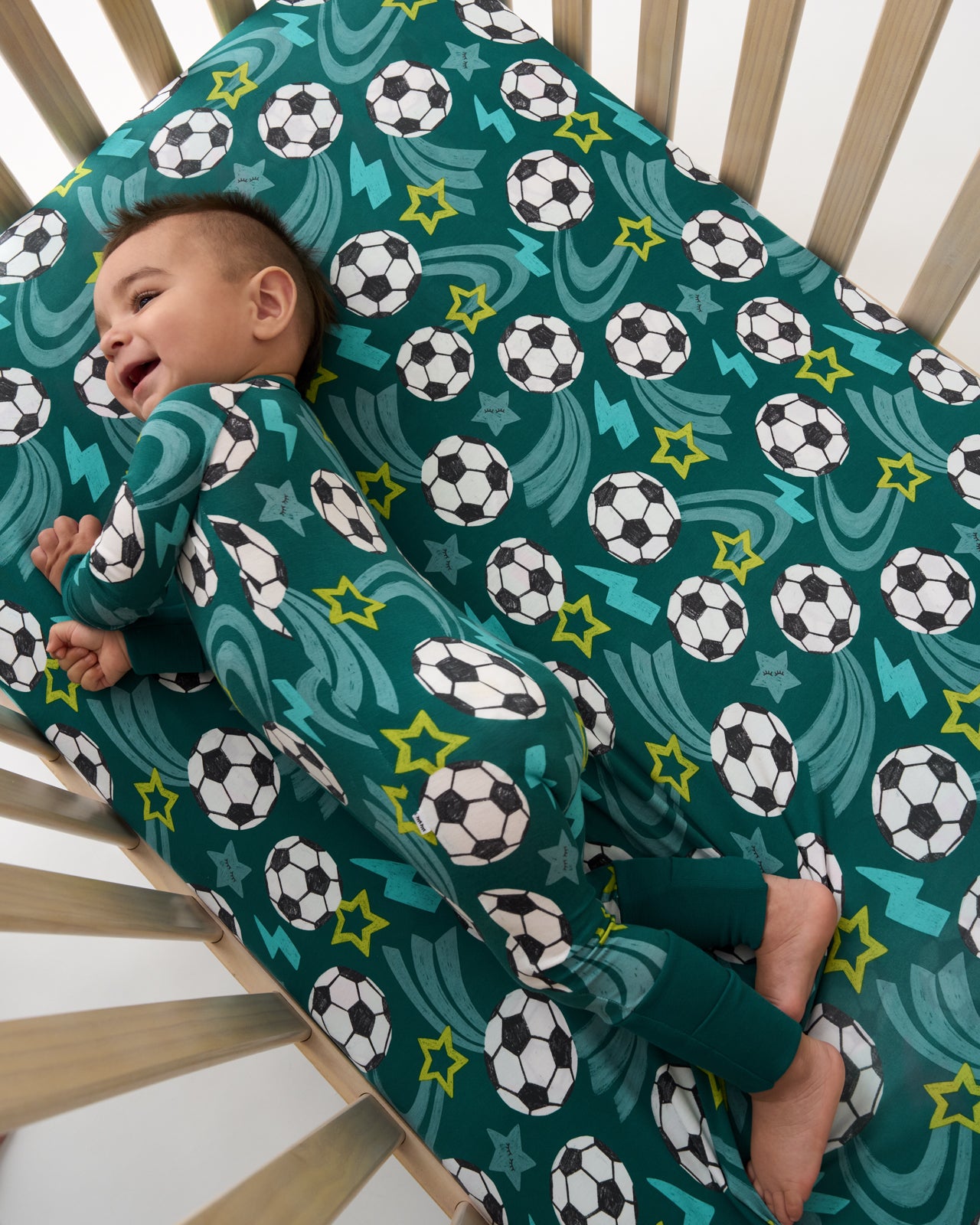 Aerial view of baby in a crib with the Soccer Stars Fitted Crib Sheet