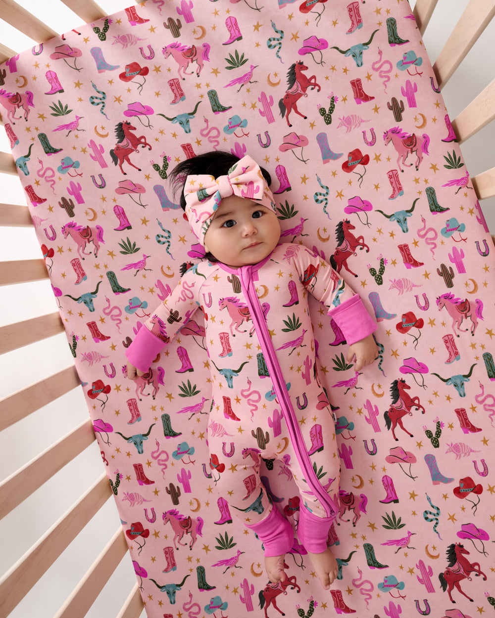 Aerial view of baby laying on the Pink Rancher Roundup Fitted Crib Sheet