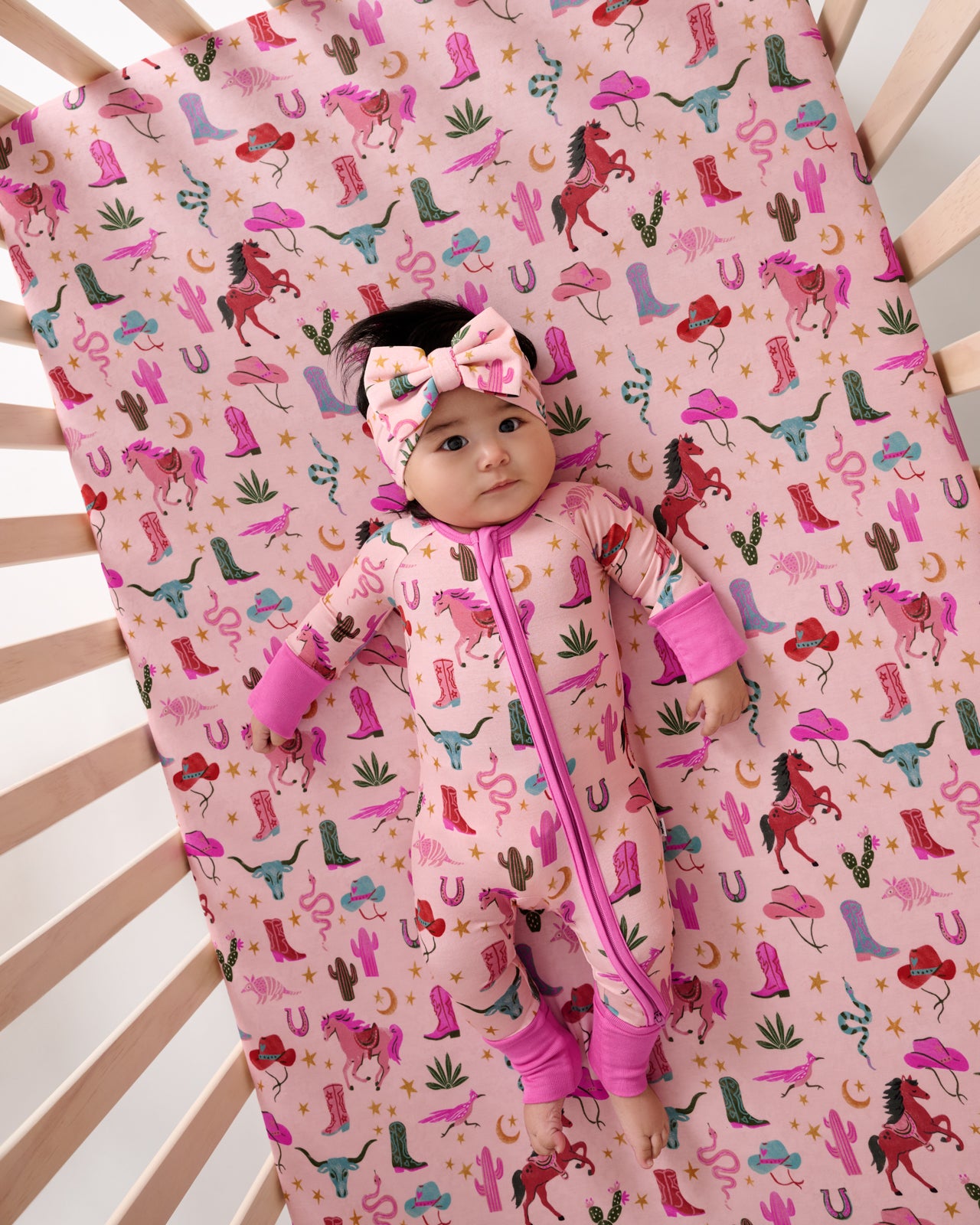 Aerial view of baby laying on the Pink Rancher Roundup Fitted Crib Sheet