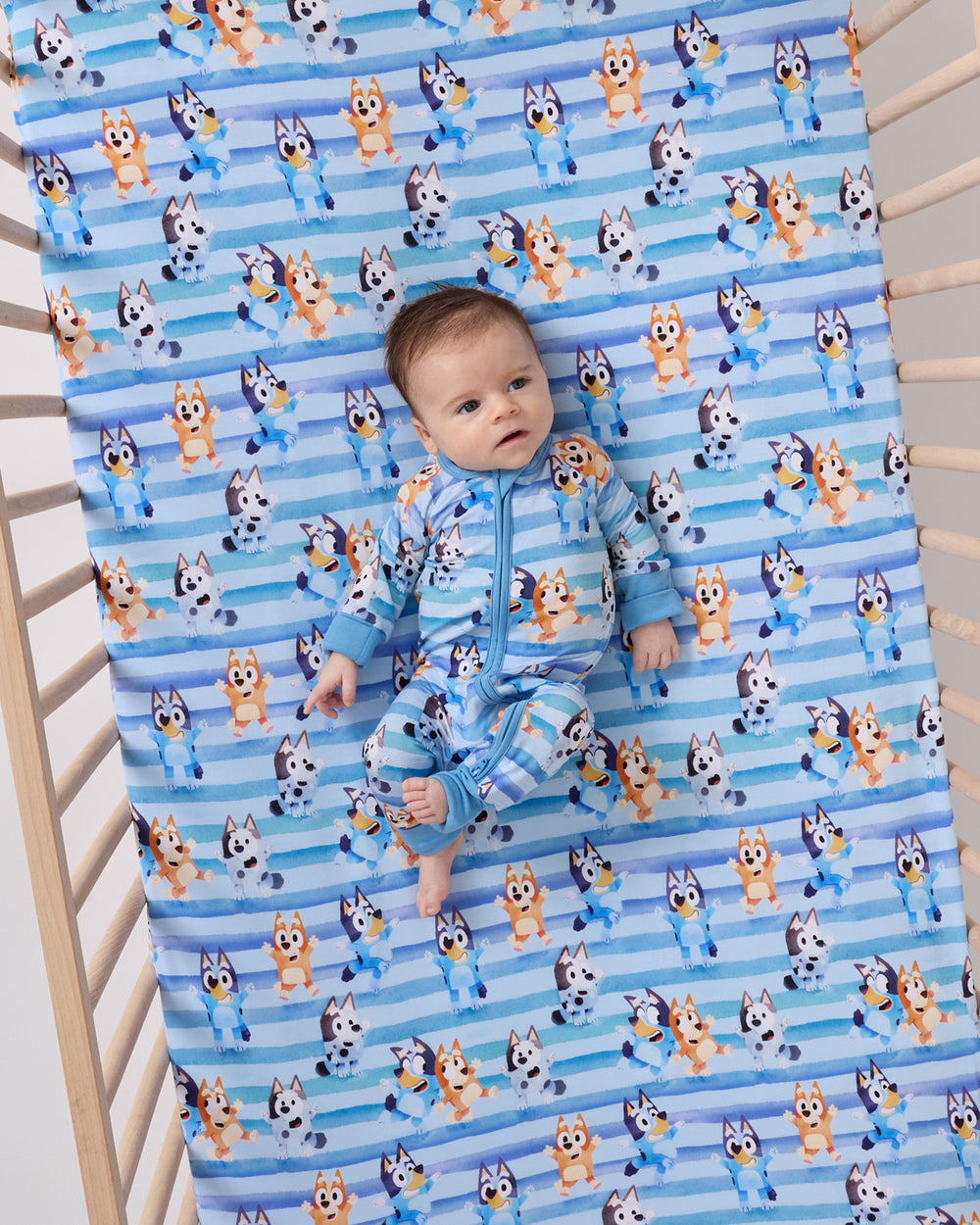 Aerial view of baby laying on the Bluey Dance All Day Fitted Crib Sheet