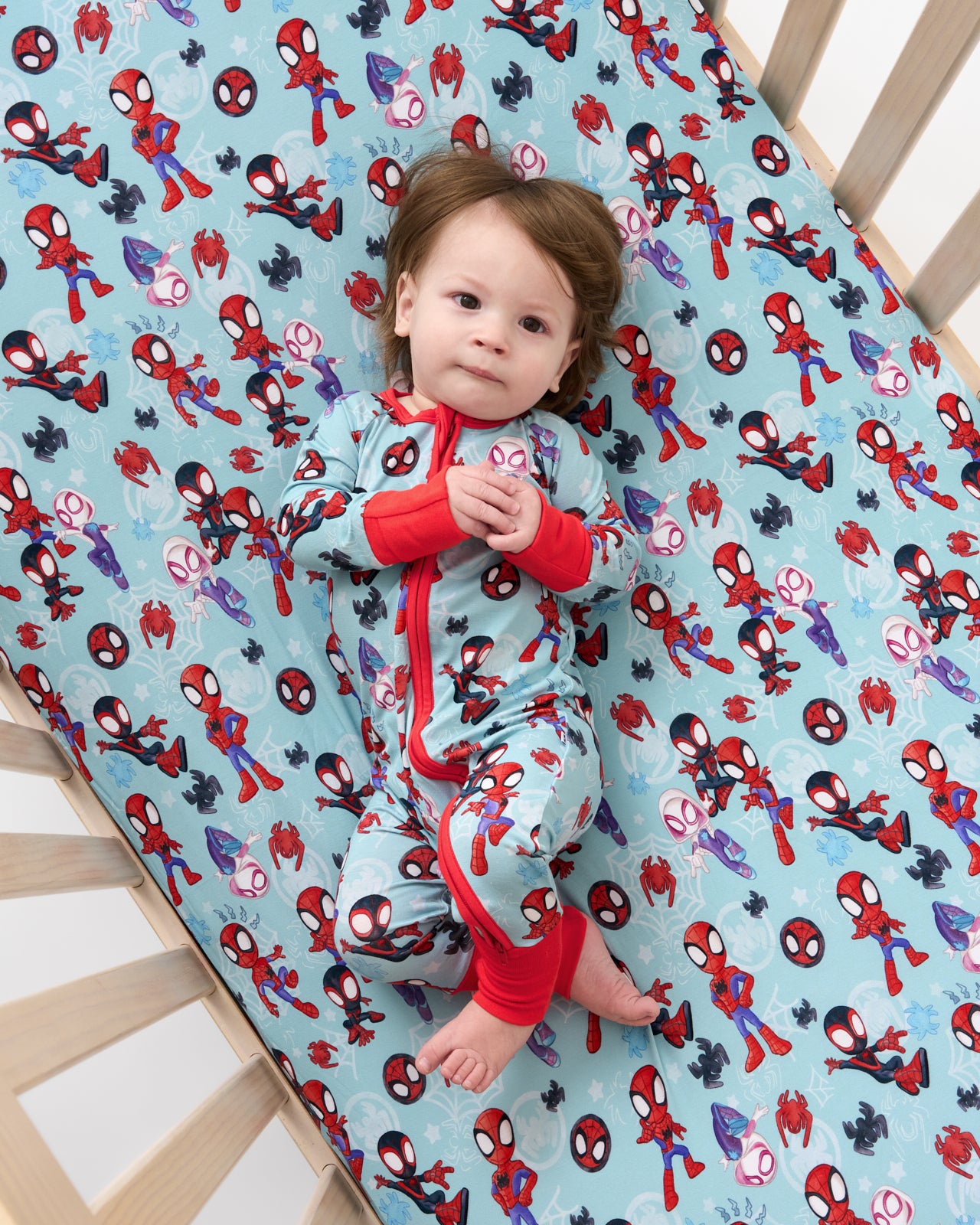 Aerial view of baby wearing the Spidey & Friends Tiny Webs Zippy on the Spidey & Friends Tiny Webs Fitted Crib Sheet