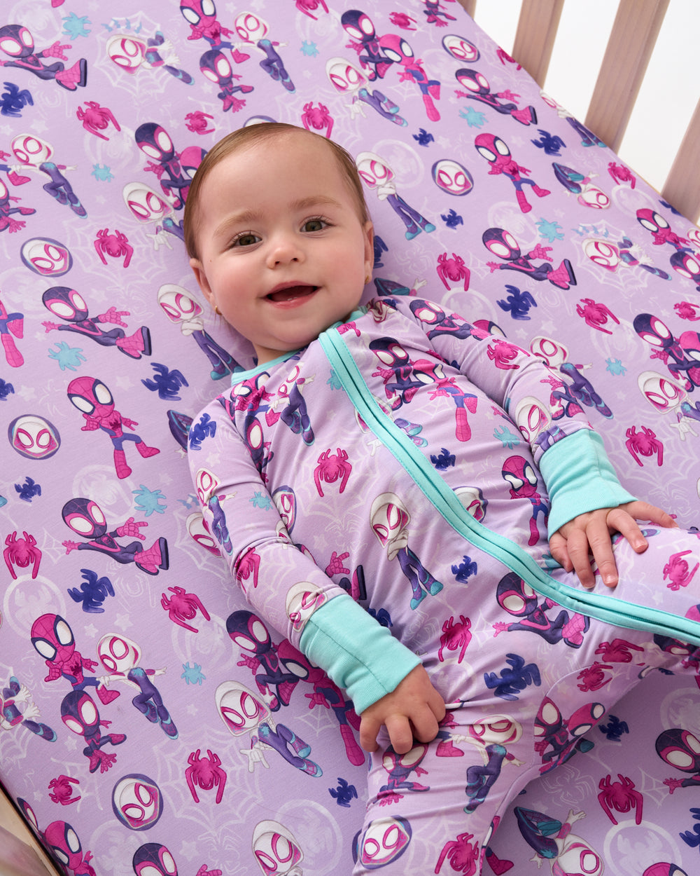 Aerial view baby laying on the Purple Spidey & Friends Tiny Webs Fitted Crib Sheet