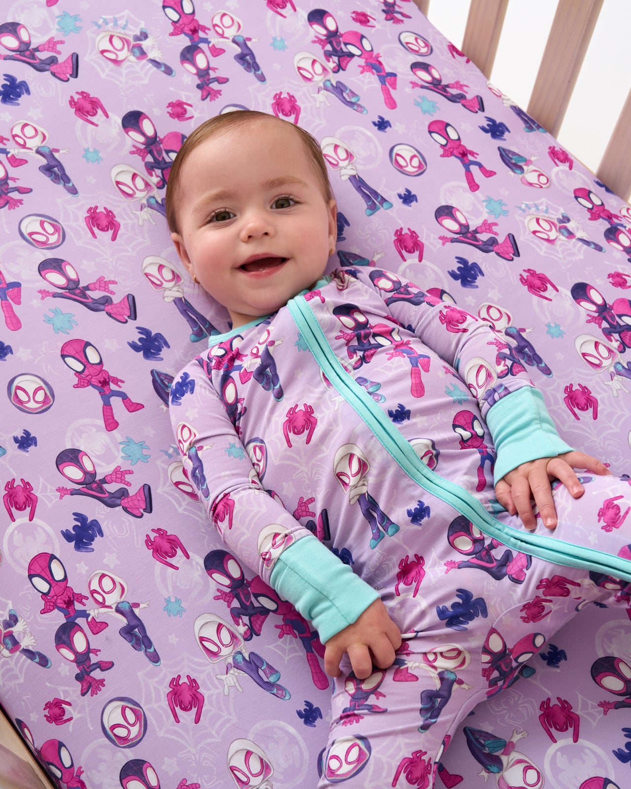 Aerial view baby laying on the Purple Spidey & Friends Tiny Webs Fitted Crib Sheet
