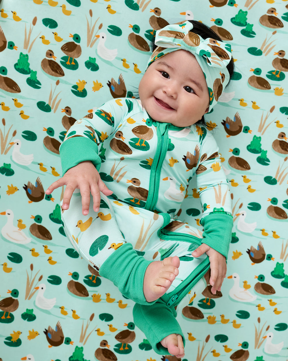 Baby laying on the Puddle Jumpers Fitted Crib Sheet wearing a matching zippy pajama