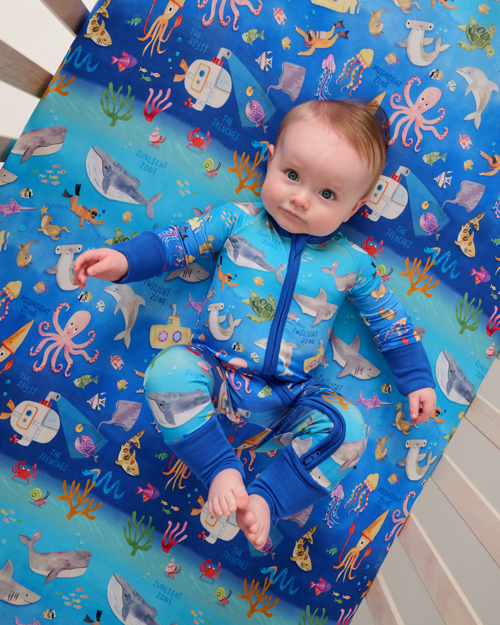 Overhead view of newborn laying on the Underwater Discovery Fitted Crib Sheet