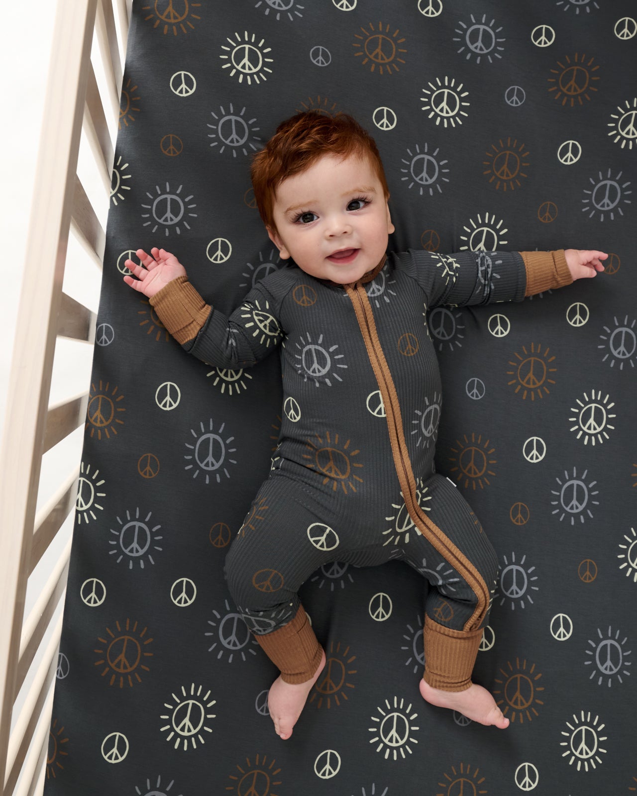 Aerial view of baby laying on the Peace & Love Fitted Crib Sheet