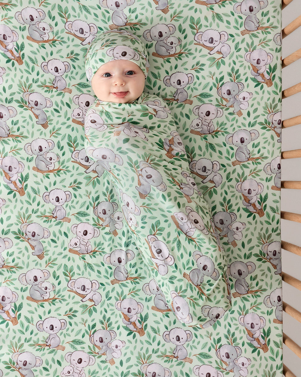 Newborn laying on the Koala Cuddles Fitted Crib Sheet